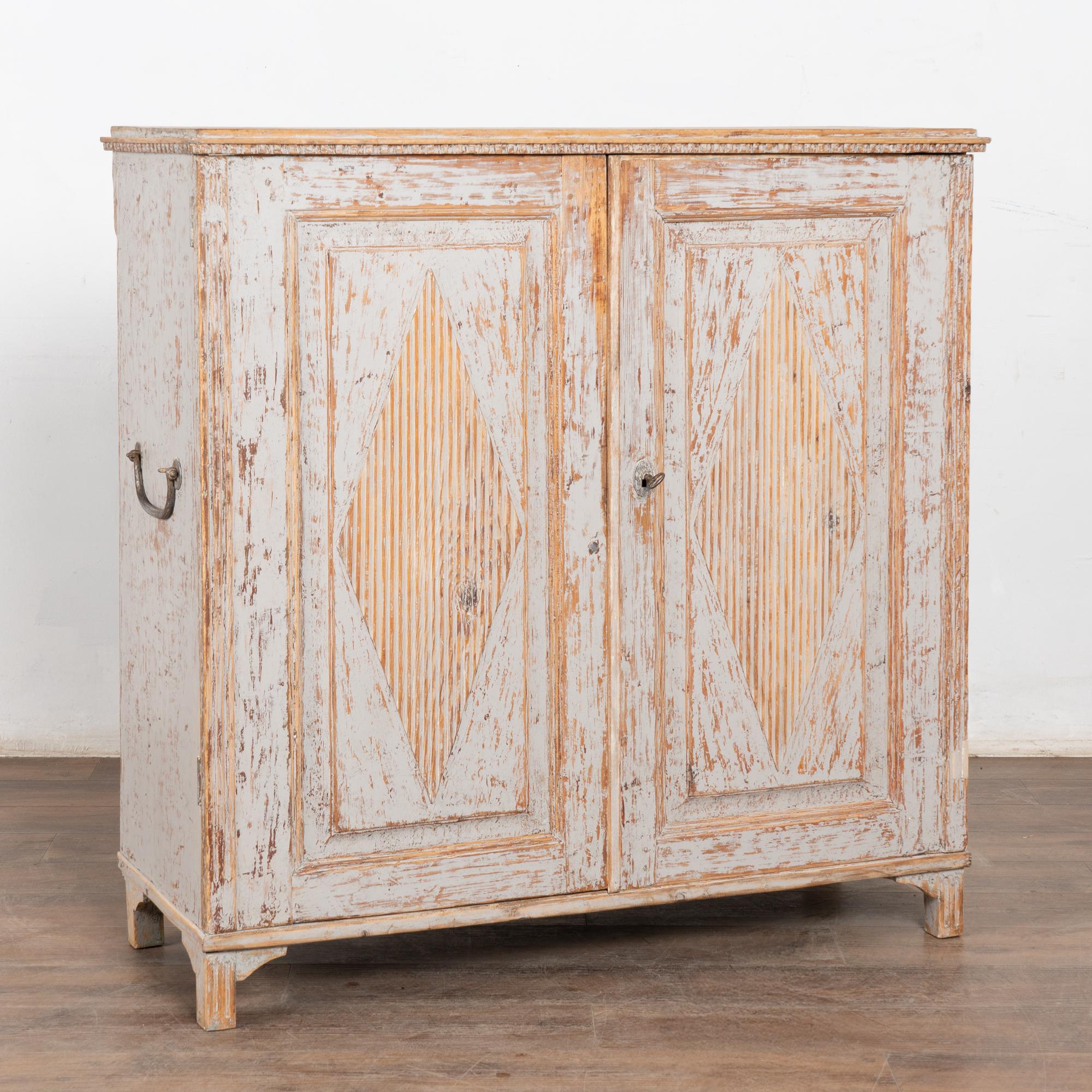 The attractive soft color pallet of this Swedish pine cabinet or console comes from the hand-painted antique gray finish which has been gently scraped and softly distressed through generations of use, resulting in the warm aged patina of the natural