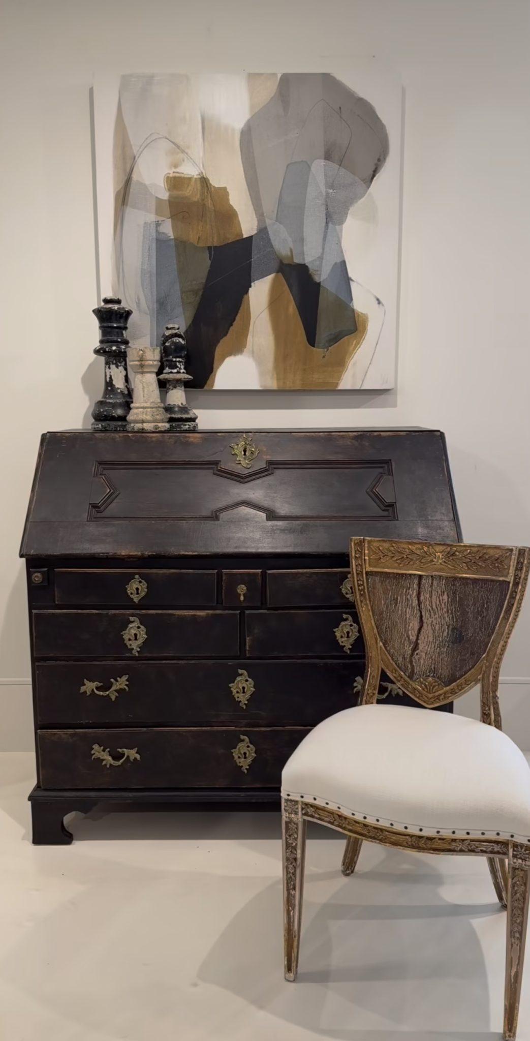 Questo grazioso scrittoio gustaviano a ribalta del XIX secolo è caratterizzato da un coperchio dipinto con eleganti pannelli che racchiudono un interno attrezzato. Le maniglie decorate contrastano perfettamente con la vernice nera patinata.
