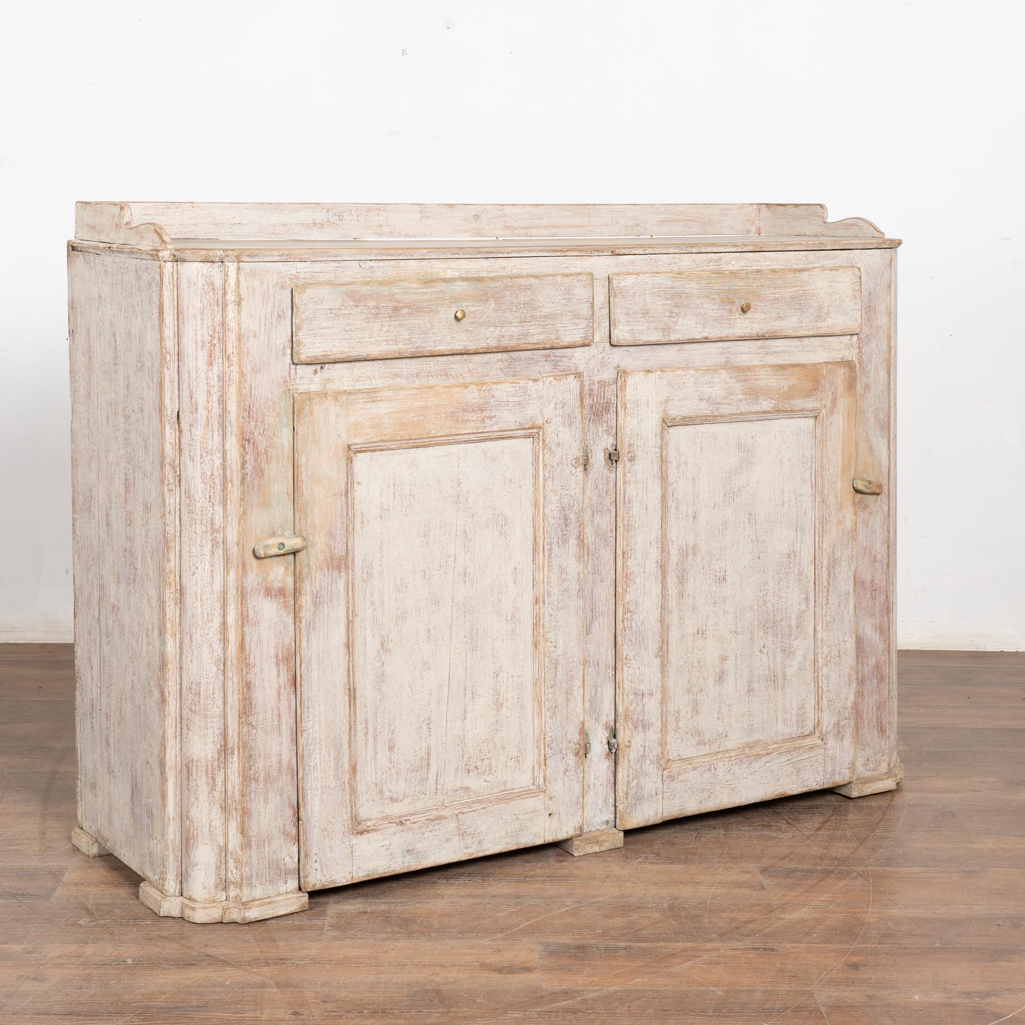 Buffet ou meuble de service gustavien en pin peint en gris clair avec deux tiroirs sur deux portes et un simple rebord autour des côtés supérieurs et de l'arrière.
La finition peinte plus récente, appliquée par des professionnels, en gris doux