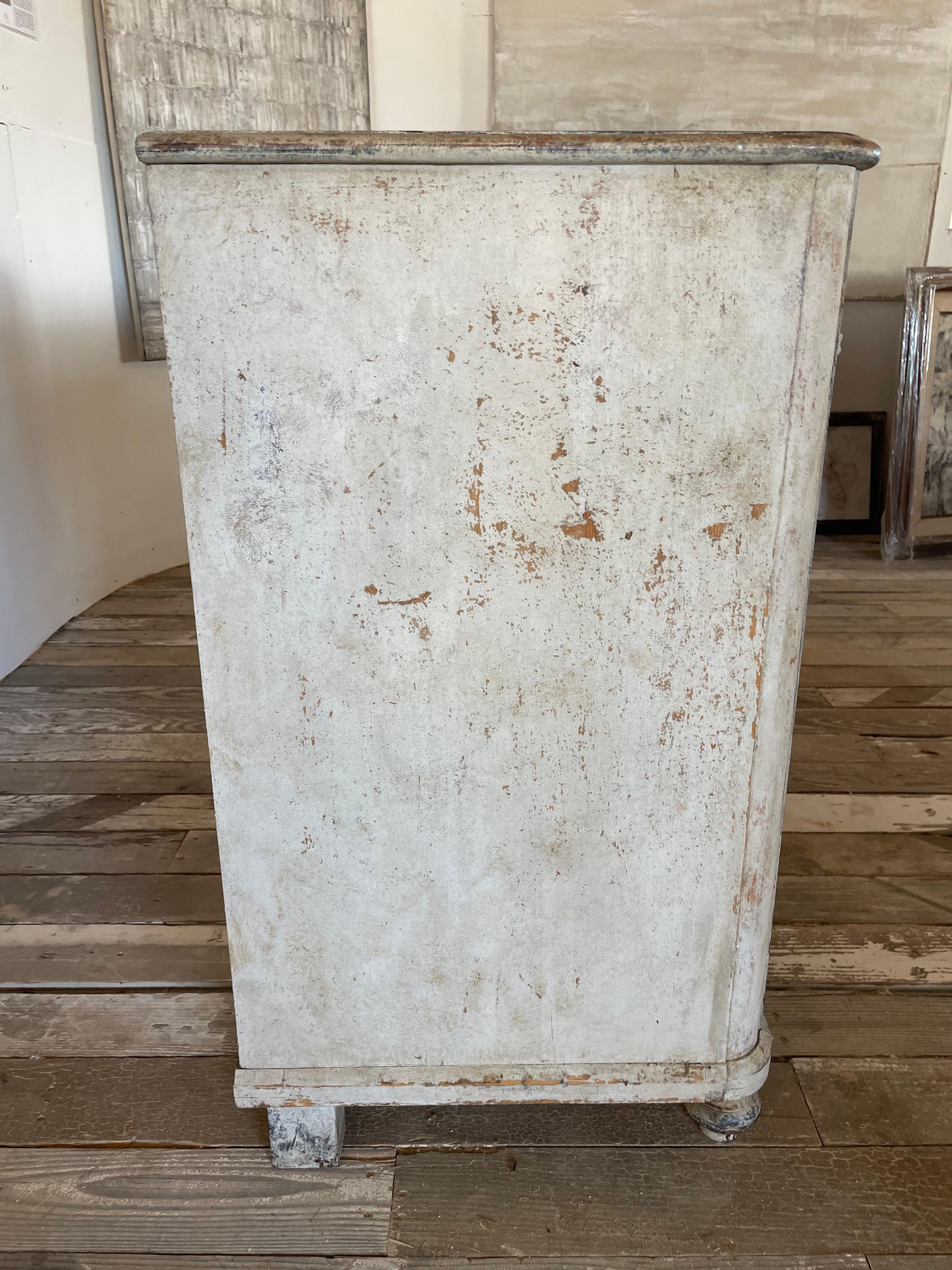 A beautiful minimalist 19th Century Swedish Gustavian painted buffet. This unique piece features 3 drawers and 3 doors. One of a kind and is a total statement piece that can go in many different directions whether it be a wabi sabi, minimalist,