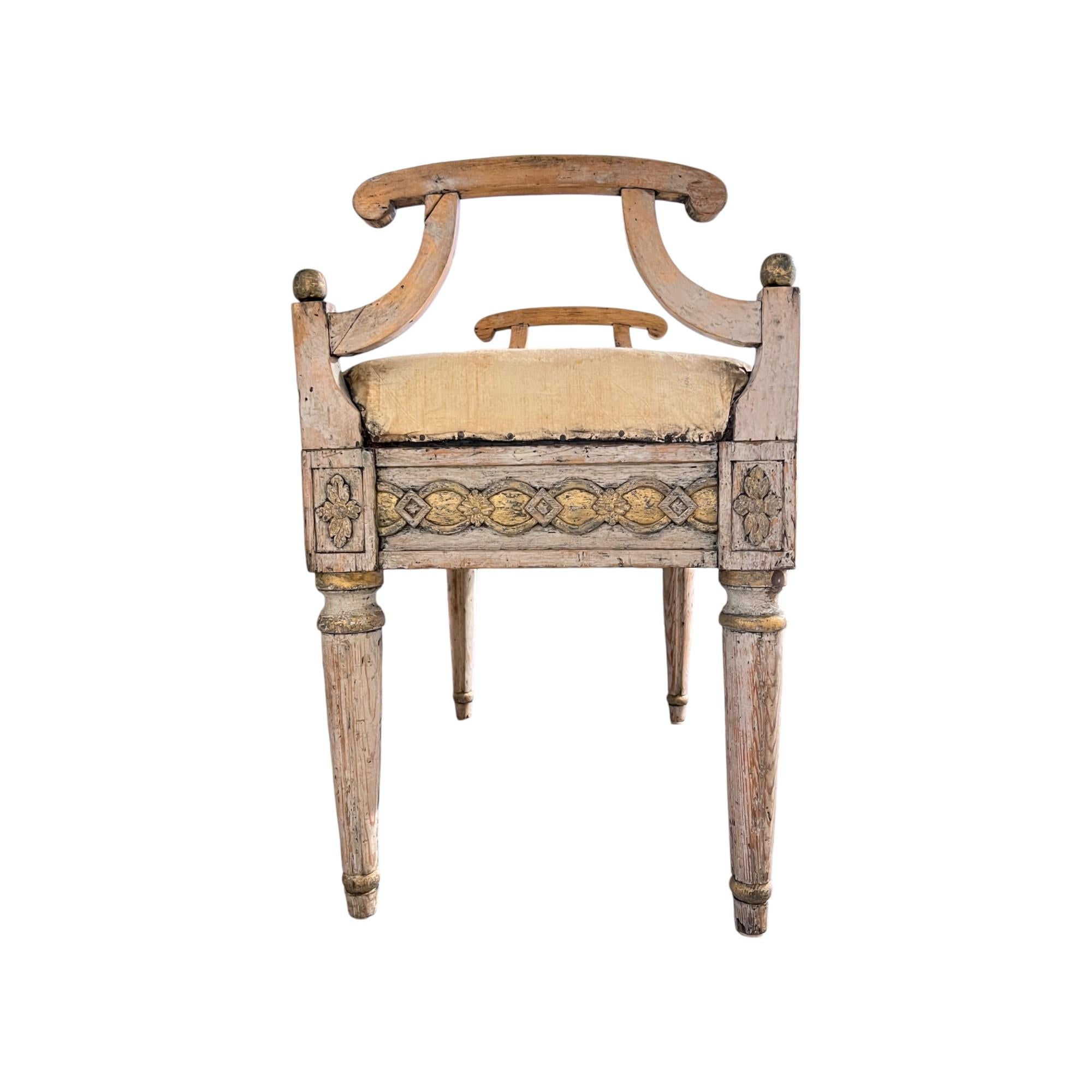 Un elegante banco Gustaviano con un suave acabado pintado y refinados detalles dorados, con detalles neoclásicos tallados y patas estriadas, que captura la sobria grandeza y ligereza del diseño sueco de finales del siglo XVIII.