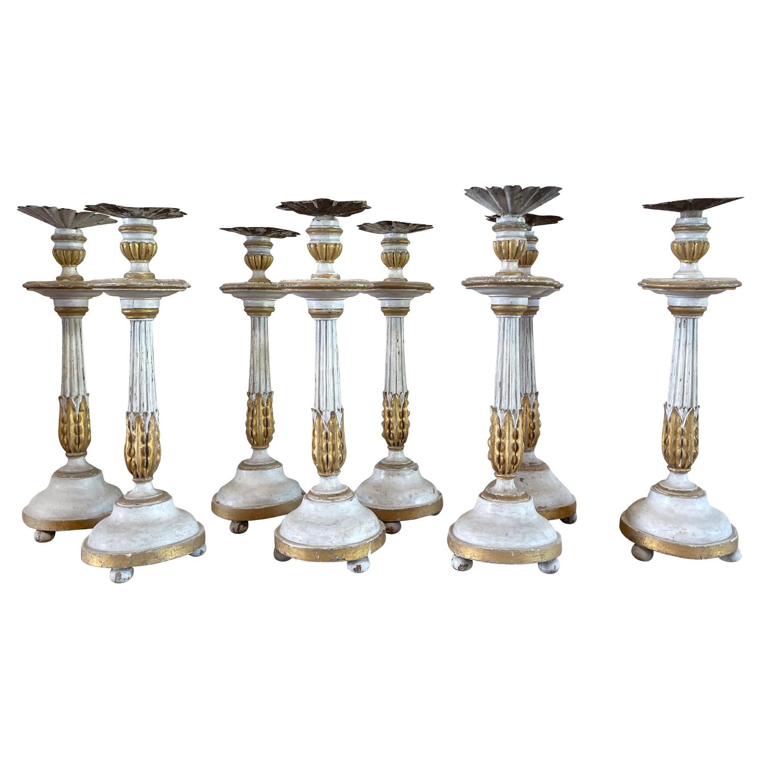 An antique Swedish pair of mid 19th Century Gustavian candle holders made of hand crafted Pinewood, in good condition. The sticks are patinated in white with gilded décor Acanthus leaves and elevated by three small feet. Topped with a metal plate
