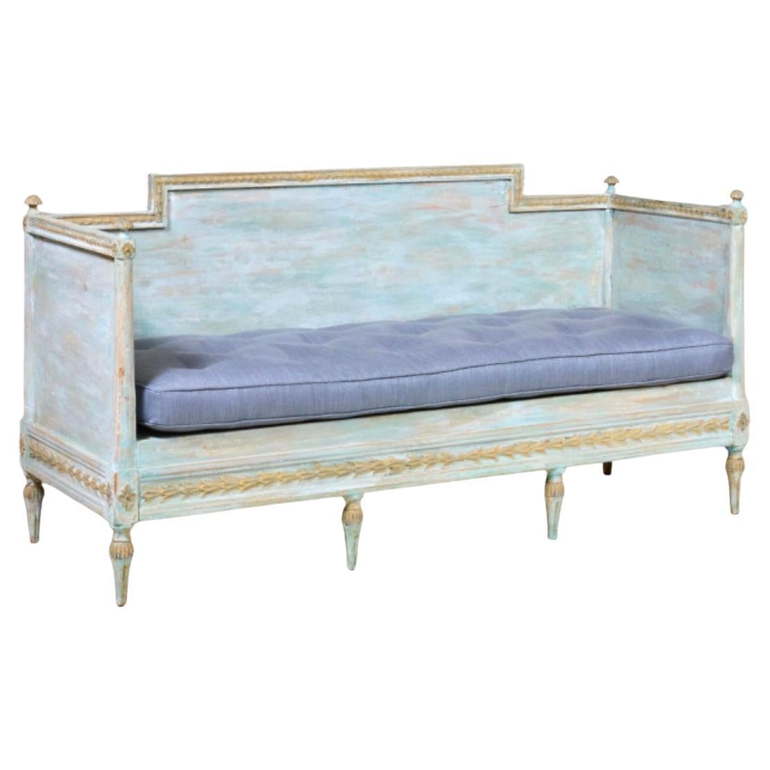 Sofá-cama sueco del periodo Gustaviano raspado a mano hasta su pintura original, con un bonito asiento tapizado. El marco presenta un motivo guilloché y las patas cónicas y acanaladas están adornadas con tapas redondas estriadas. La parte trasera