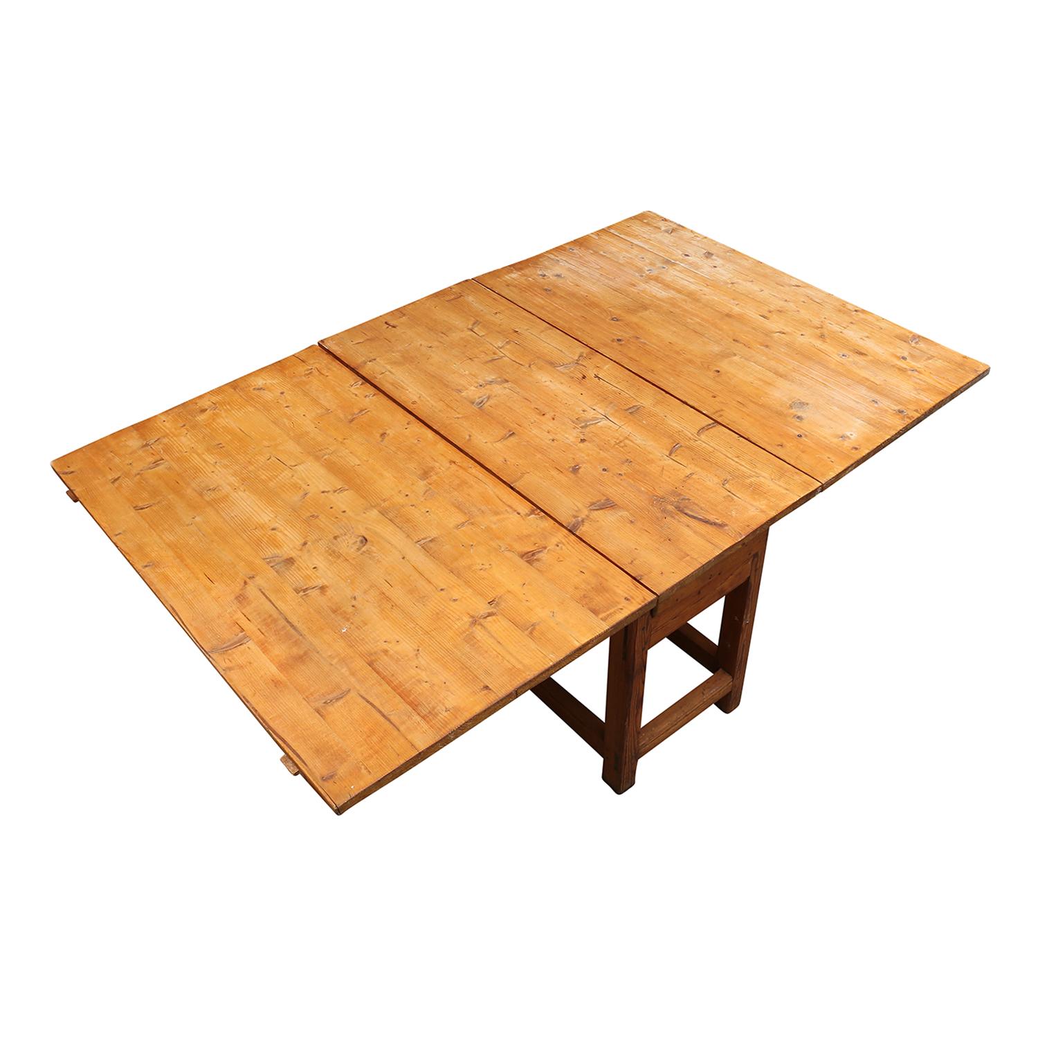 An antique Swedish Gustavian Slagbord, drop-leaf table with one drawer, made of hand crafted Pinewood in good condition. The Scandinavian dining room table is supported by four round wooden legs, each leaf folds up independently, supported by two