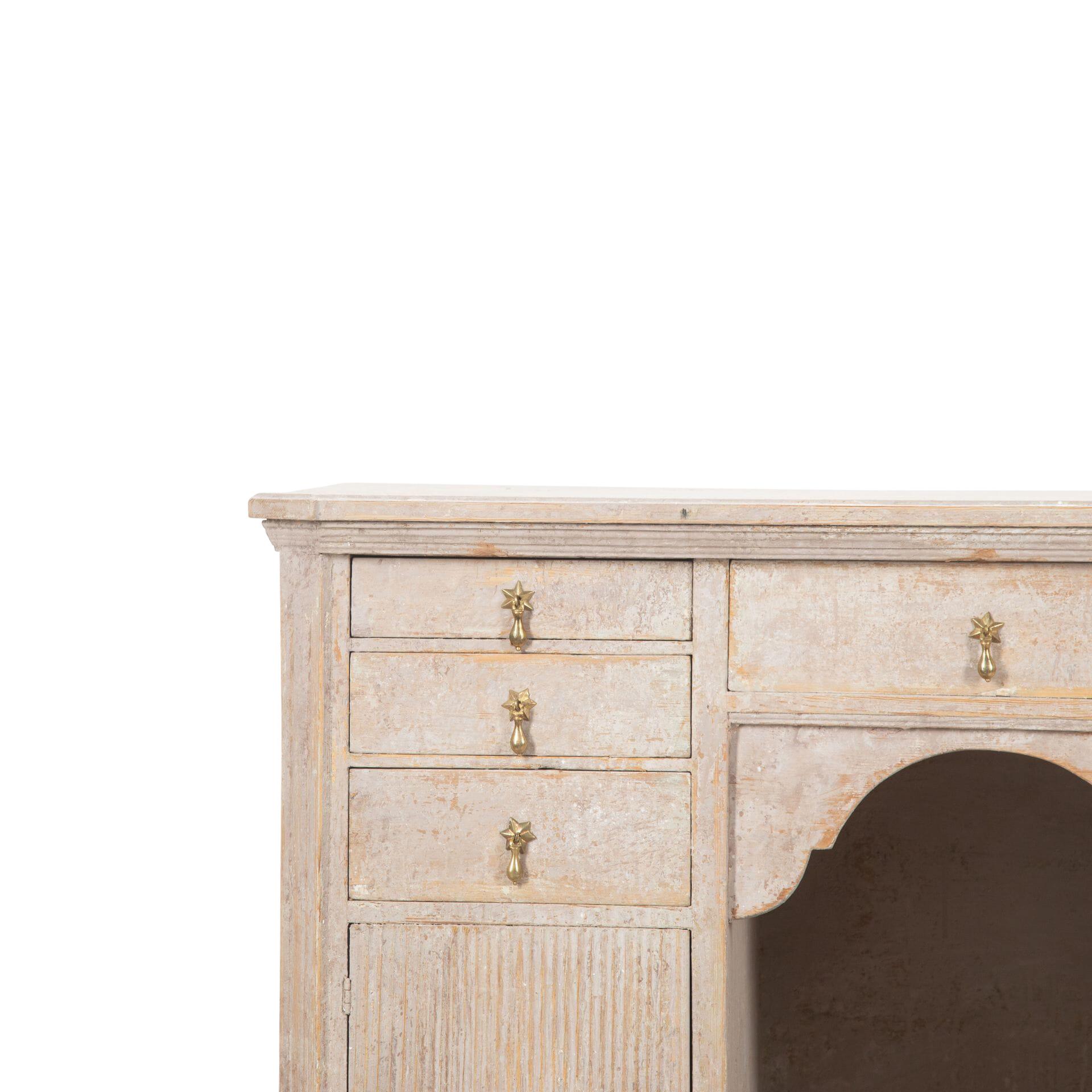 Unusual Gustavian sideboard with carved top.
Below are six short and one long drawer with decorative star handles. 
Reeded doors opening to further storage.