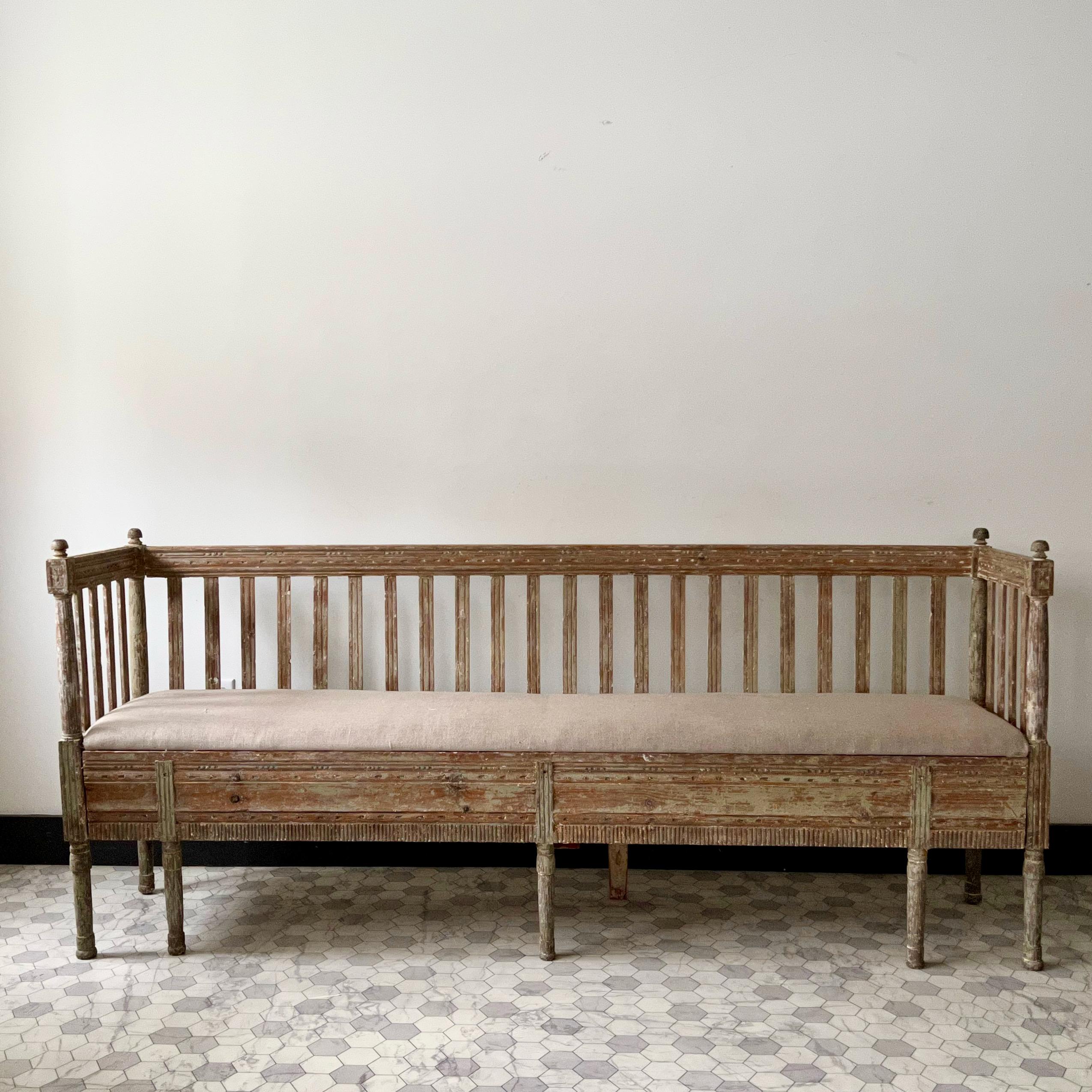 Early 19th century Swedish Gustavian sofa with carved decoration around the apron and storage/bed underneath the seat. 
Hand dry-scraped to its most original color and newly upholstered seat in linen.
Long and narrow sofa practical in tight areas.