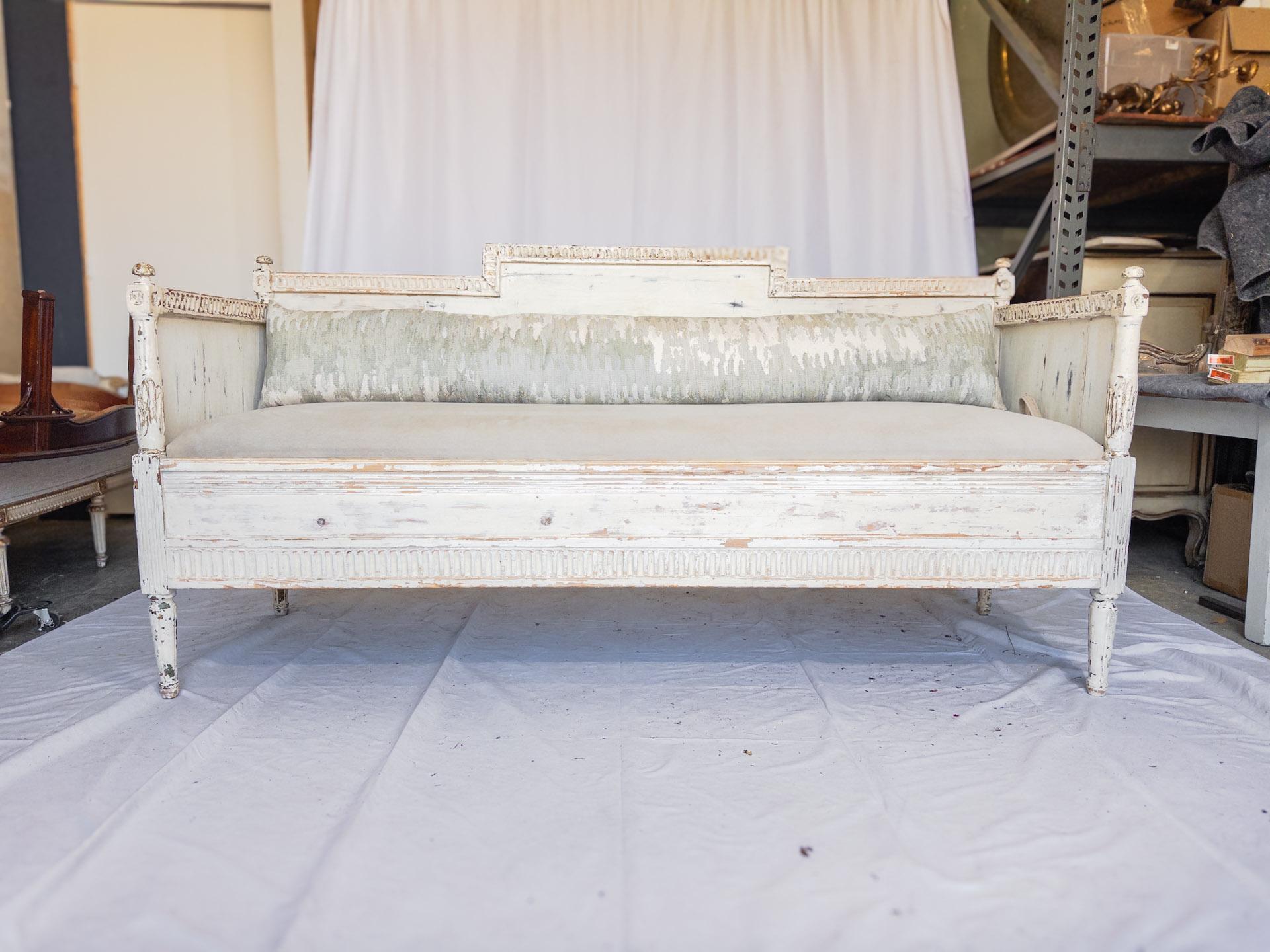 The 19th Century Swedish Gustavian Style Painted Sofa Bench exemplifies the elegance and sophistication of Gustavian furniture design. Carved with meticulous detail, this piece showcases the craftsmanship and artistry of the era. Its graceful lines