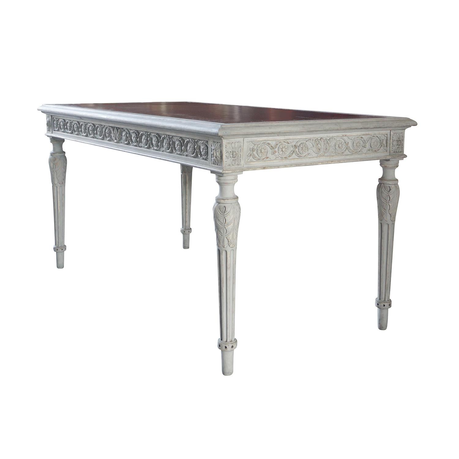 An antique Swedish Gustavian freestanding writing table made of pinewood with a grey paint and a dark red leather top. The Scandinavian, richly hand carved desk is in good condition, detailed in the neoclassical Greek style, enhanced by very