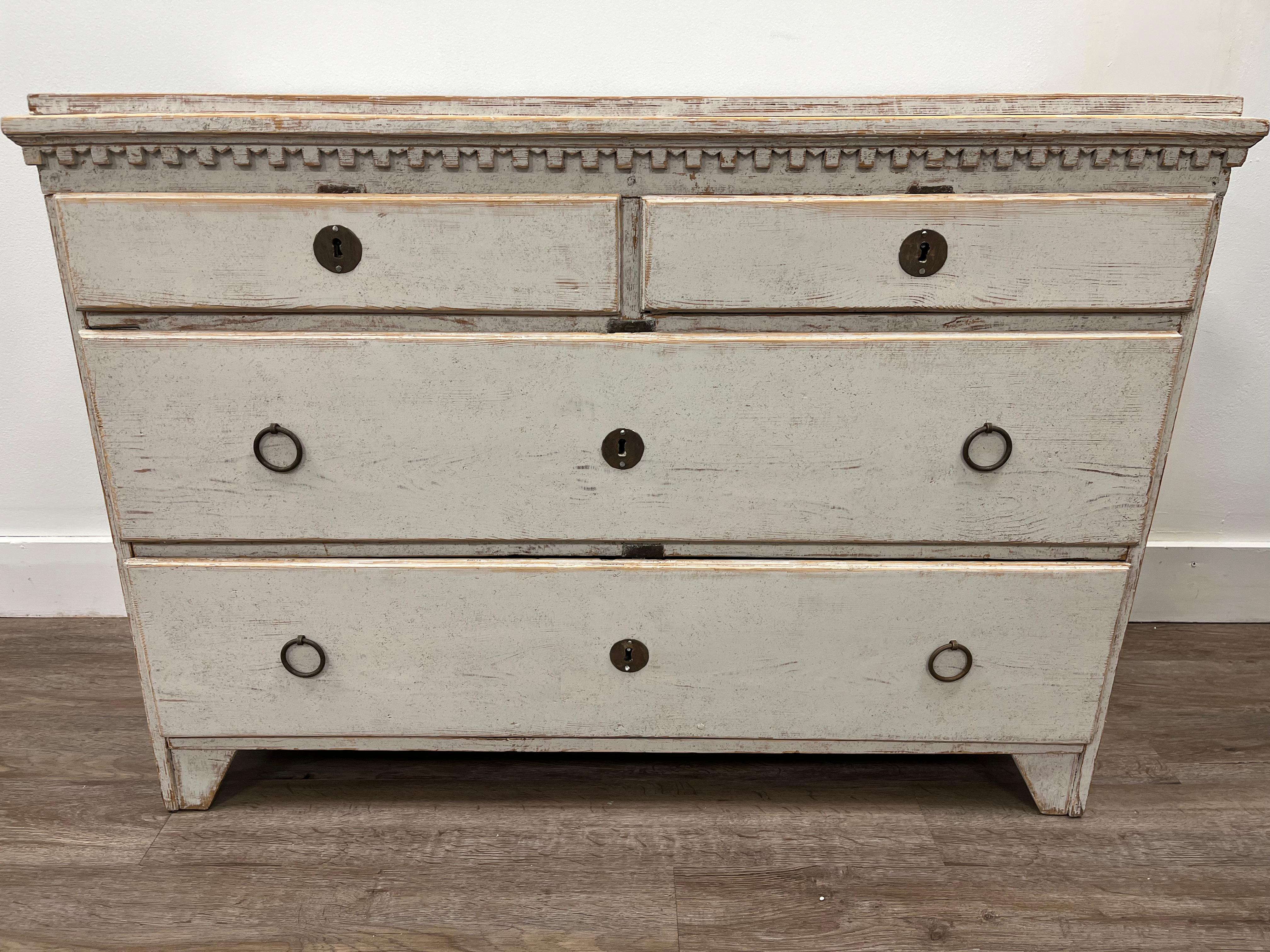 A low provincial Late Gustavian chest of drawers with later iron hardware and original locks. Repainted in light grey. Dental frieze top over two small and two large drawers. 
