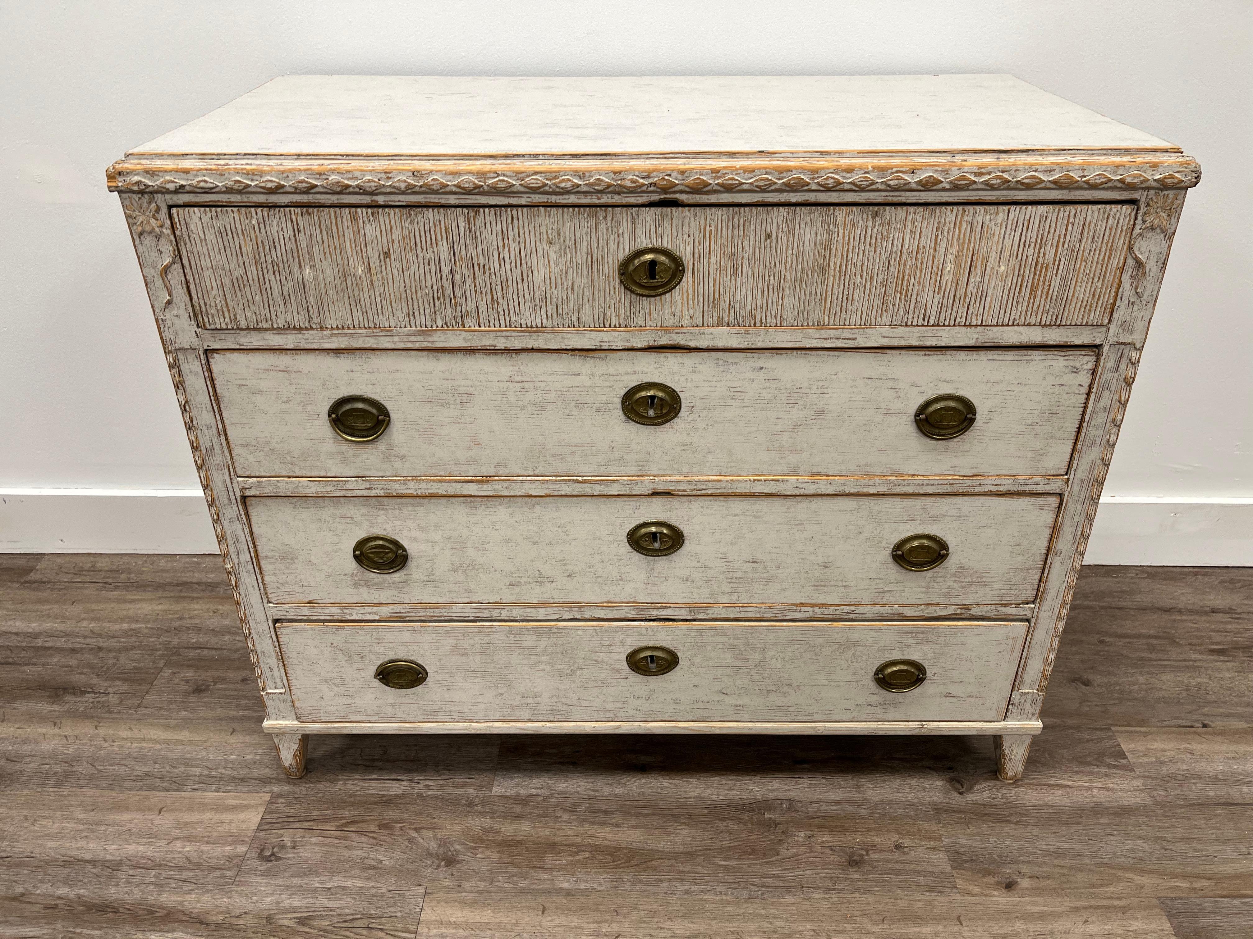 A provincial Late Gustavian chest of drawers with unusual wood carvings - diamond detailing across the top and sides, a heavily vertical reeded top drawer front, floral medallions in the upper corners and vertical front frames that are both recessed