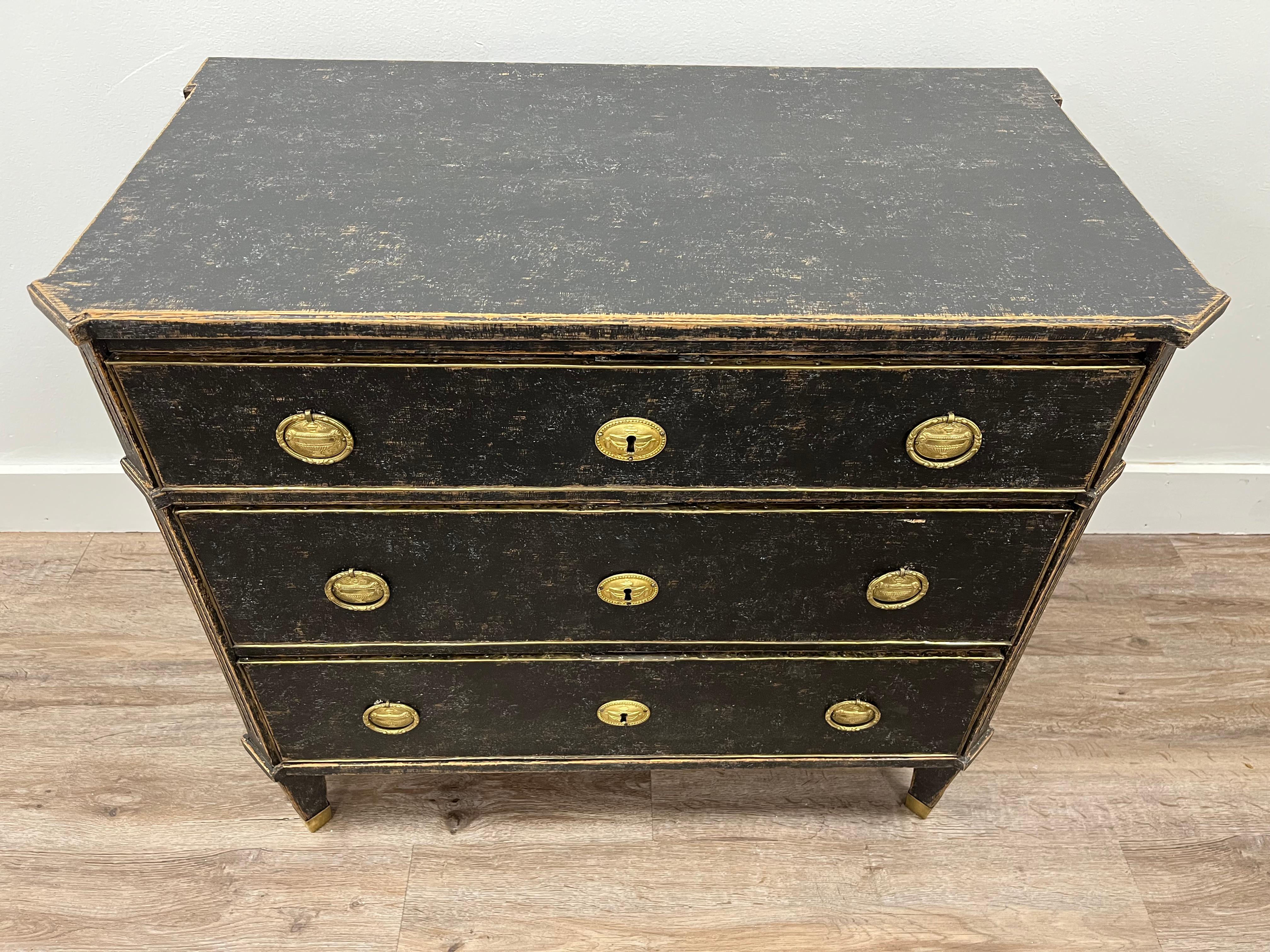 A Swedish Late Gustavian commode with original brass hardware and locks. Featuring canted and fluted corners. Drawer fronts outlined in brass. Sits on fluted and tapered feet with brass covers. Tastefully repainted in black. 