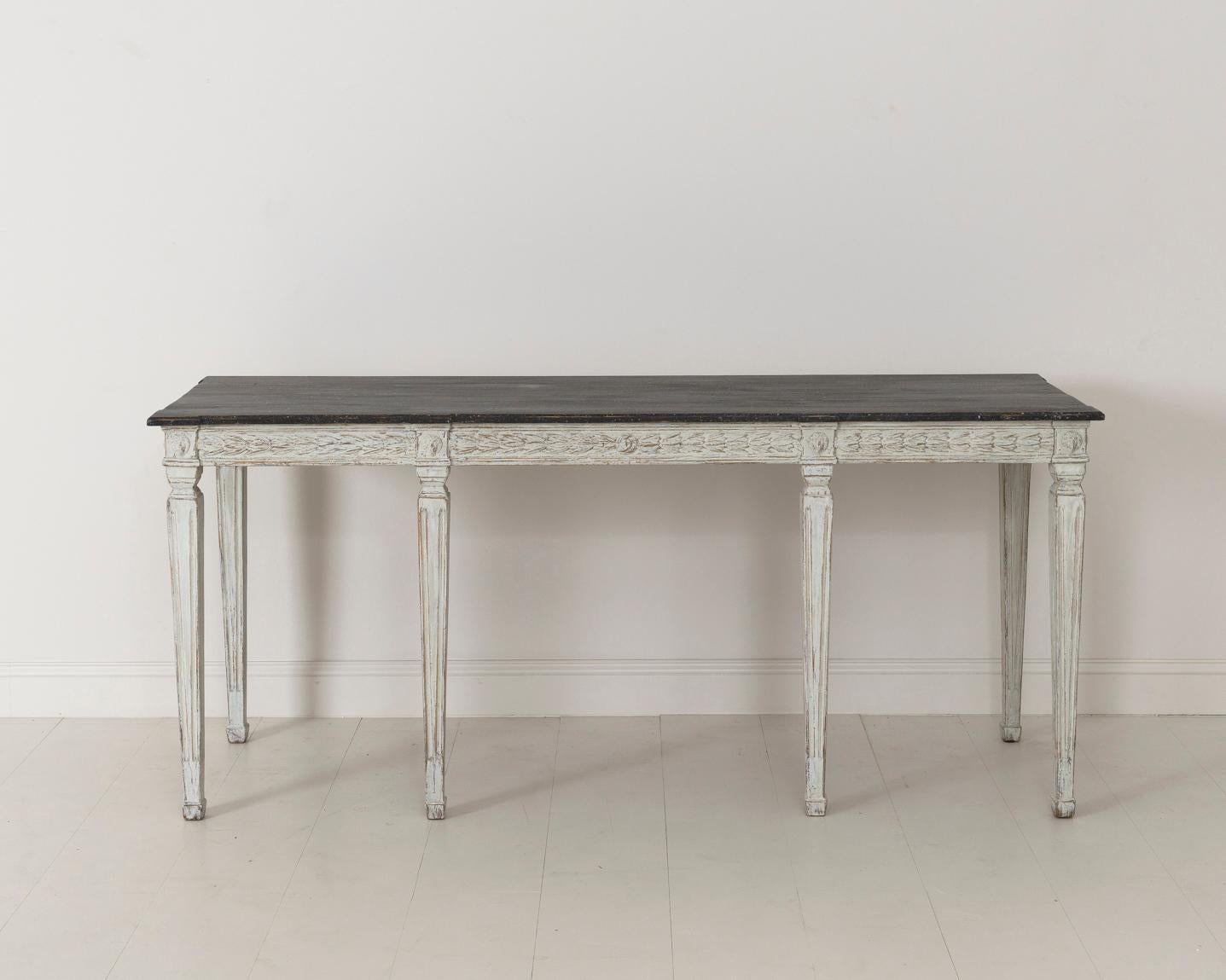Swedish late Gustavian console table from the 19th century with hand painted black porphyry top. The apron is decorated with bell flowers and the leg posts with lion heads. This beautifully classic table is raised upon square tapered and channeled