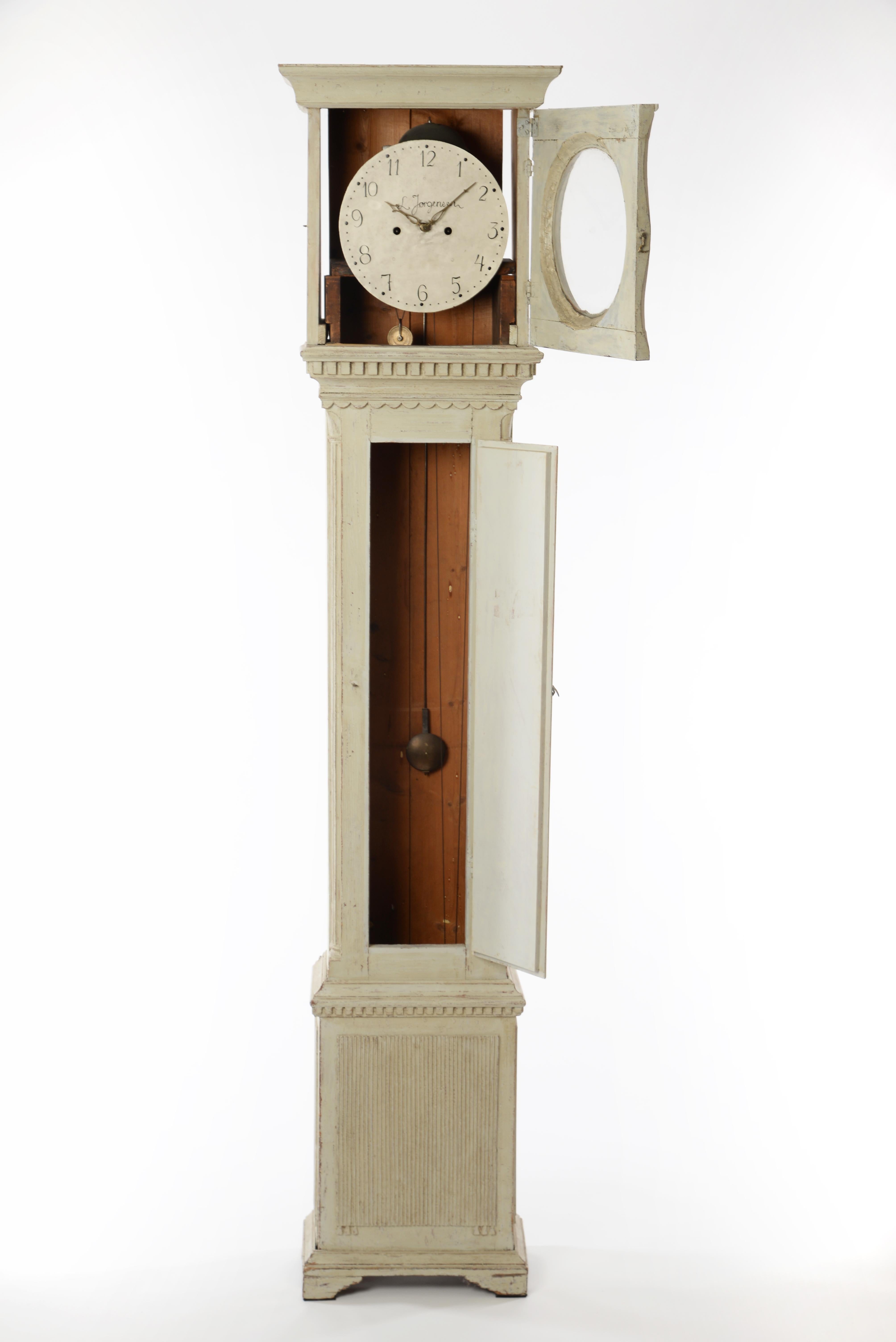 Cette belle horloge suédoise du 19e siècle, de forme allongée, présente des lignes très nettes, droites et simples. Les décorations sont exquises mais subtiles. Le visage présente des chiffres traditionnels et conserve sa face, ses aiguilles et son
