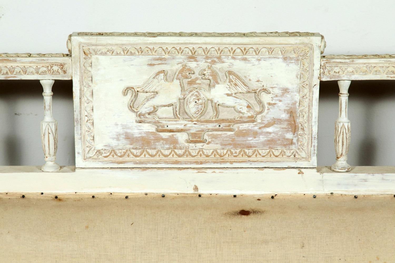 19th century Swedish neoclassical whitewashed sofa bench made in Sweden during the period 1790-1810, featuring carving all around that includes laurel drops, carved lower and upper rails, and a nicely carved back pediment with sphinxes. Needs to be