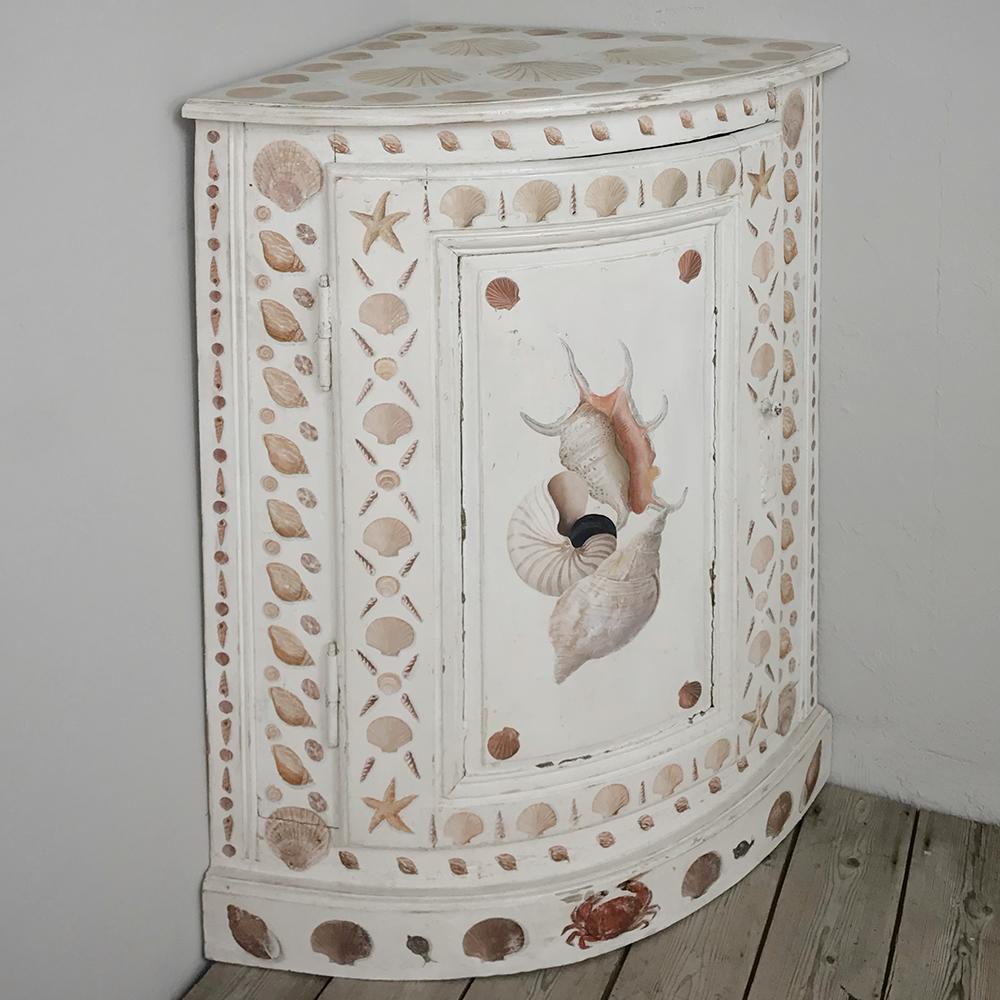 19th century Swedish painted corner cabinet features a delightful patina on the background, plus artistically excellent depictions of sea shells across the entire facade for a whimsical nautical effect! Snails, scallops, and a proud crab appear on
