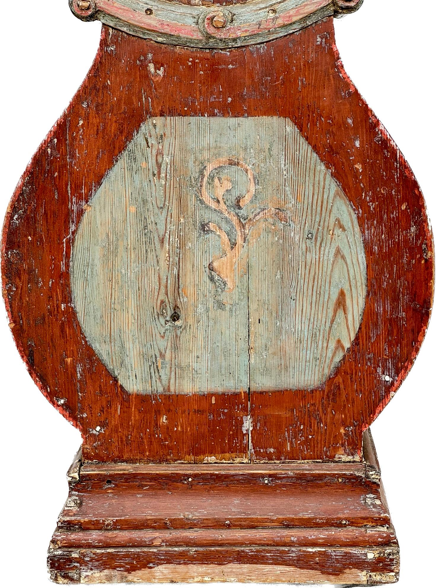 19th century Swedish Painted longcase Mora Clock, Gotland, circa 1820. Features red painted body with blue painted inserts. Clock has a painted tin face with Roman numerals encased by a round bonnet and surmounted by a gilt crest, the baluster case