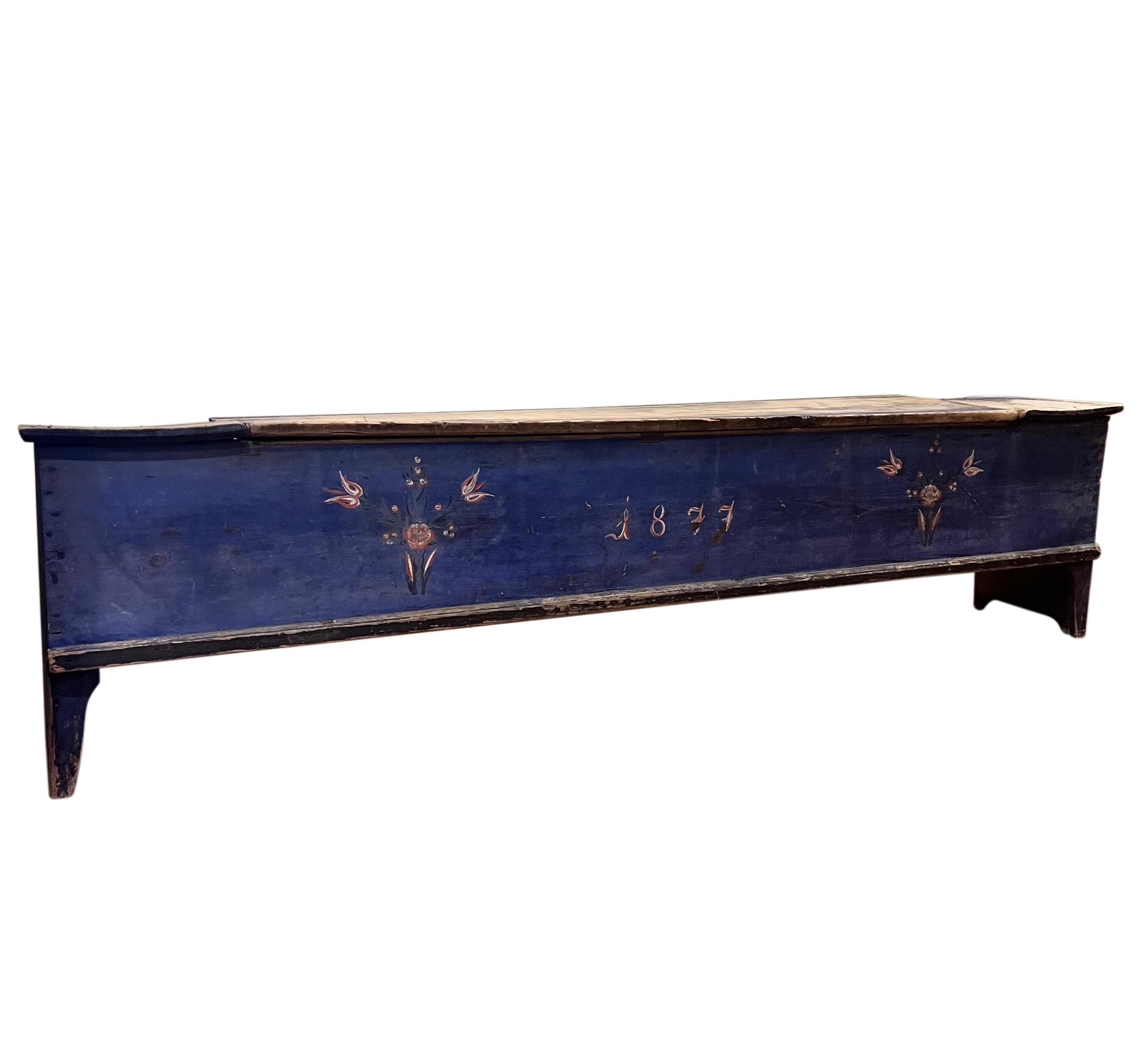 19th century Swedish folk art painted pine long chest or bench, dated 1877.

Great for both a bench and storage, it is long and narrow with a large divided section inside. The chest has age appropriate wear which adds to its character. The top is