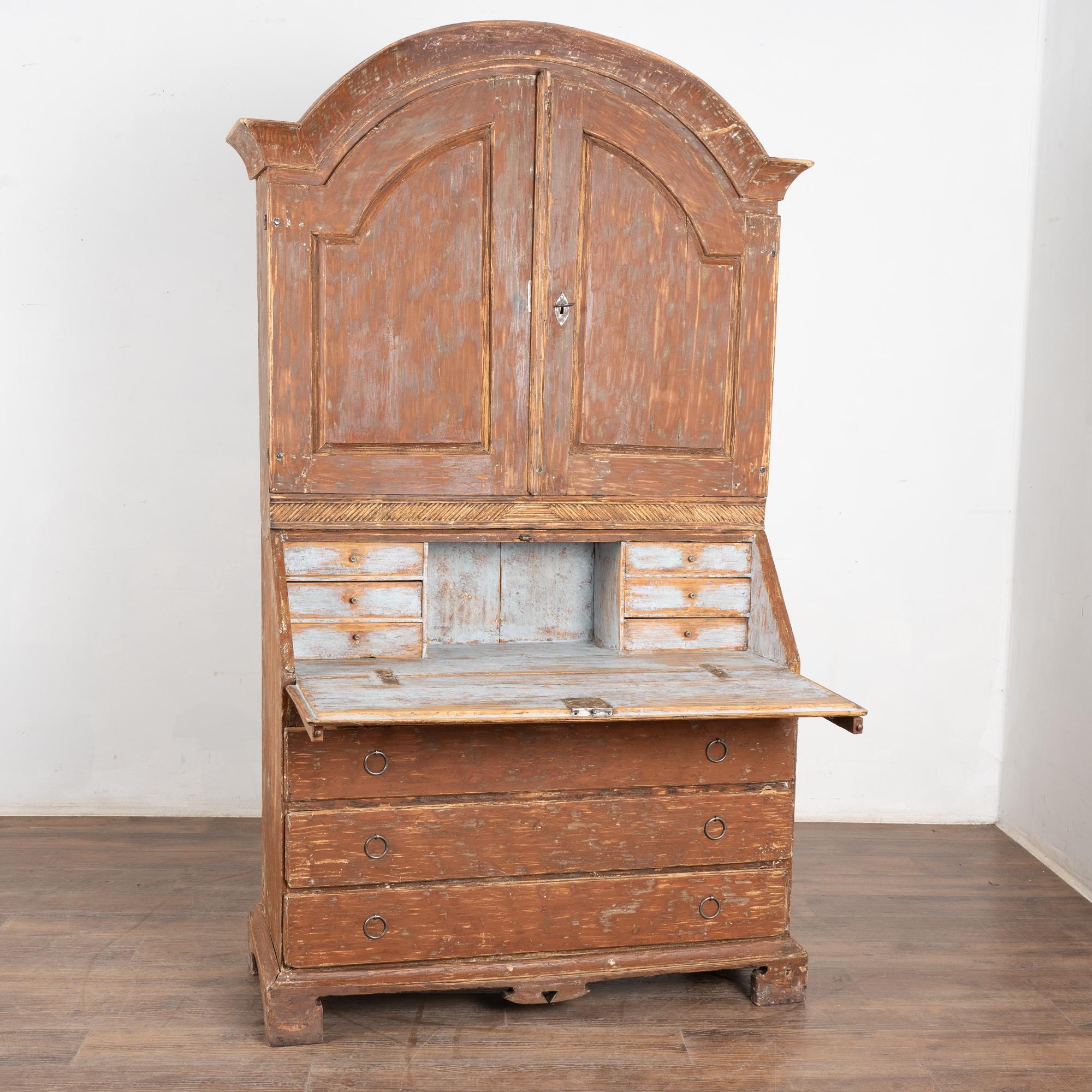 È la patina invecchiata e scrostata della finitura originale dipinta di marrone ad attirare l'attenzione su questa segretaria in pino dal grazioso fascino svedese.
La scrivania poggia su due bracci estesi. La scrivania si apre e rivela 6 piccoli