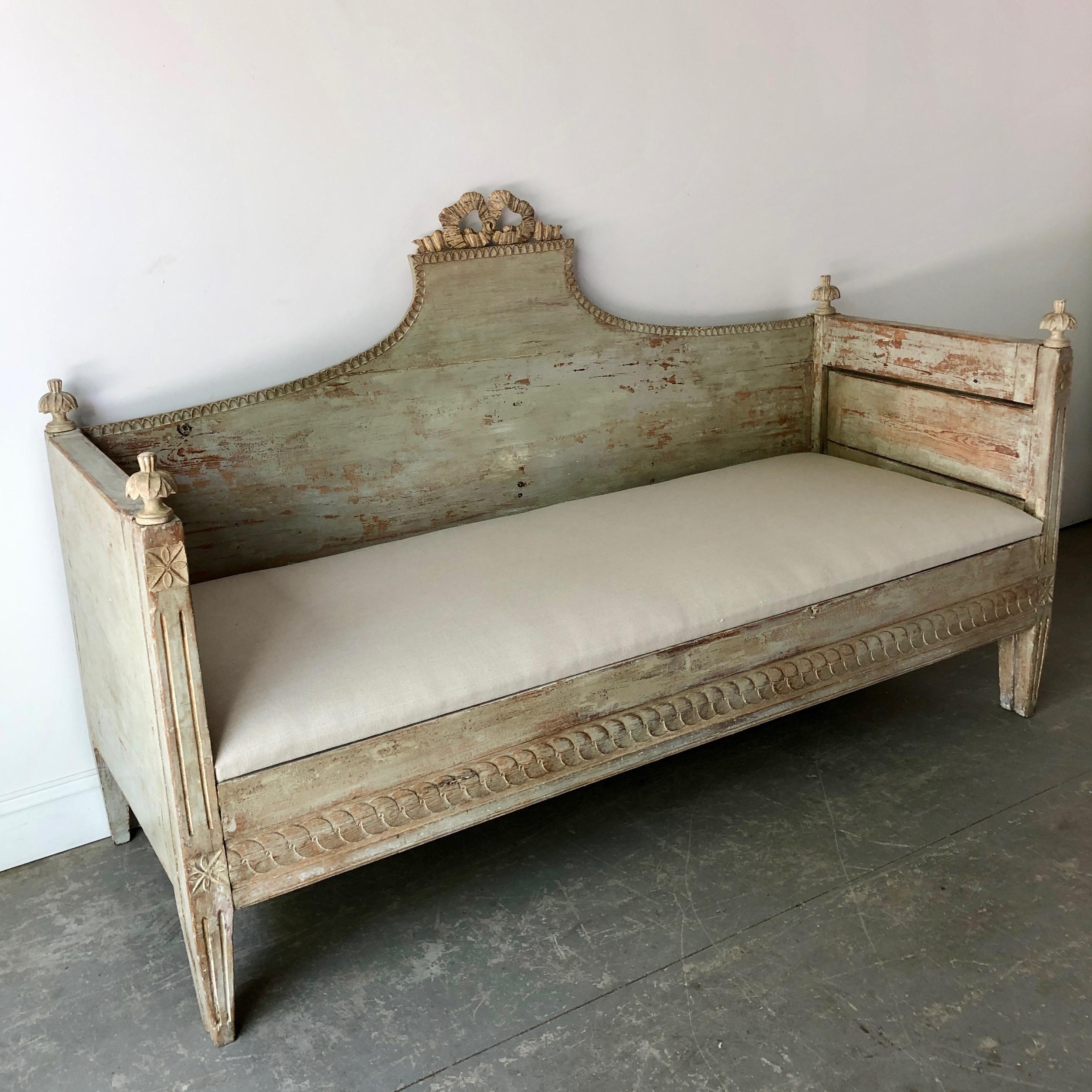 Gustavian sofa bed, Sweden circa 1850 with beautiful Gustavian details; the back and apron with richly carved. The finish has been scraped to reveal much of the original paint. Seat can be lifted off for storage and also the front section pulls out