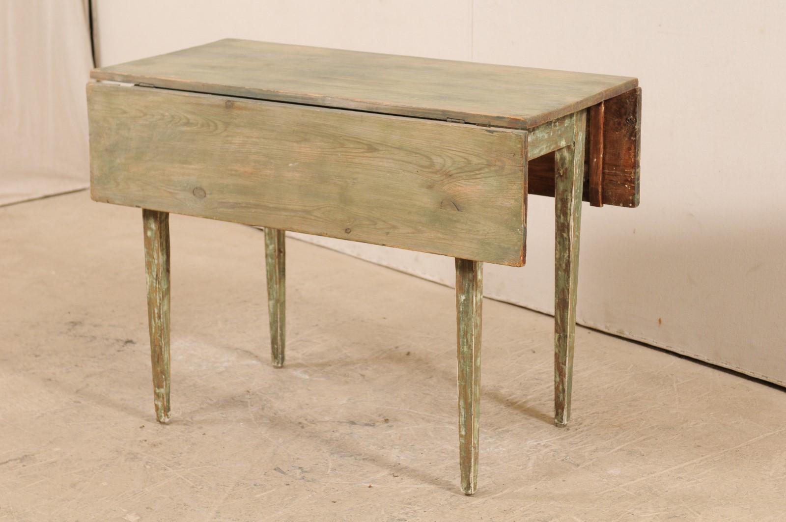 A 19th century Swedish drop-leaf wood table with original paint. This antique table from Sweden has a double drop-leaf sides, making this a very versatile piece, depending on how you use the leaf arrangements. This table has simply, clean lines, a