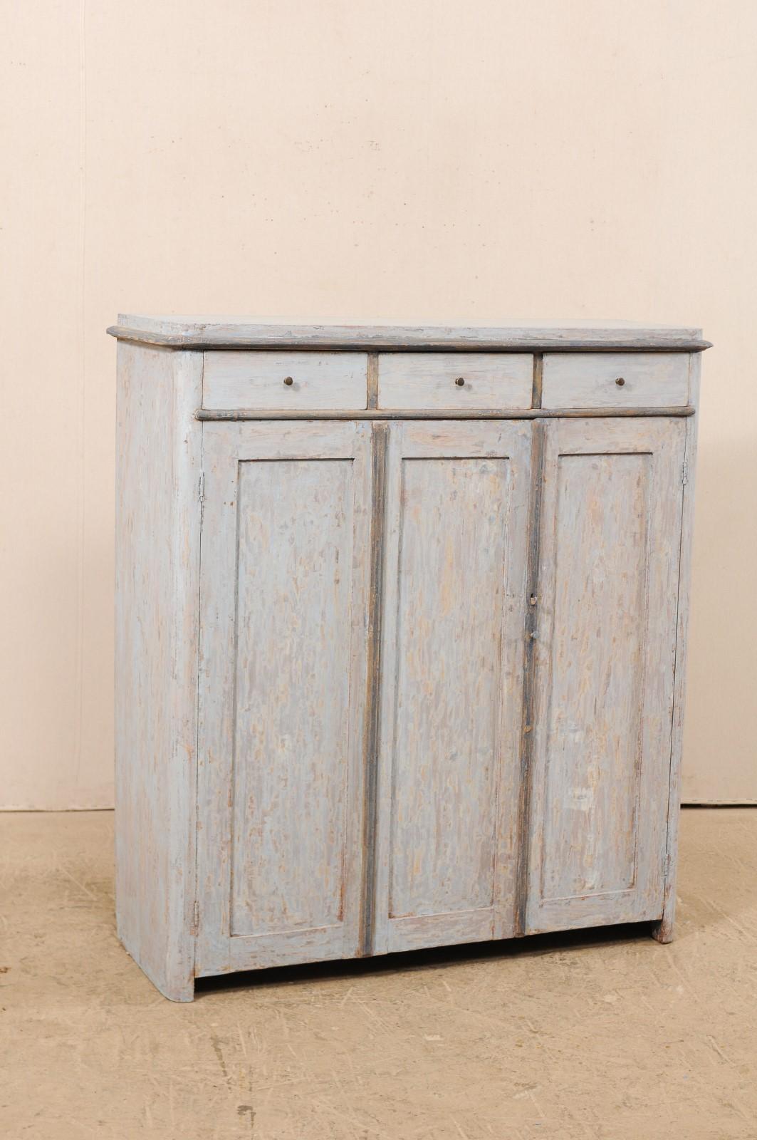 A Swedish painted wood storage cabinet from the early 19th century. This antique mid-sized cabinet from Sweden features a simple design of clean lines and has a lovely blue scraped finish, with much of the wood grain showing through, and a warmer