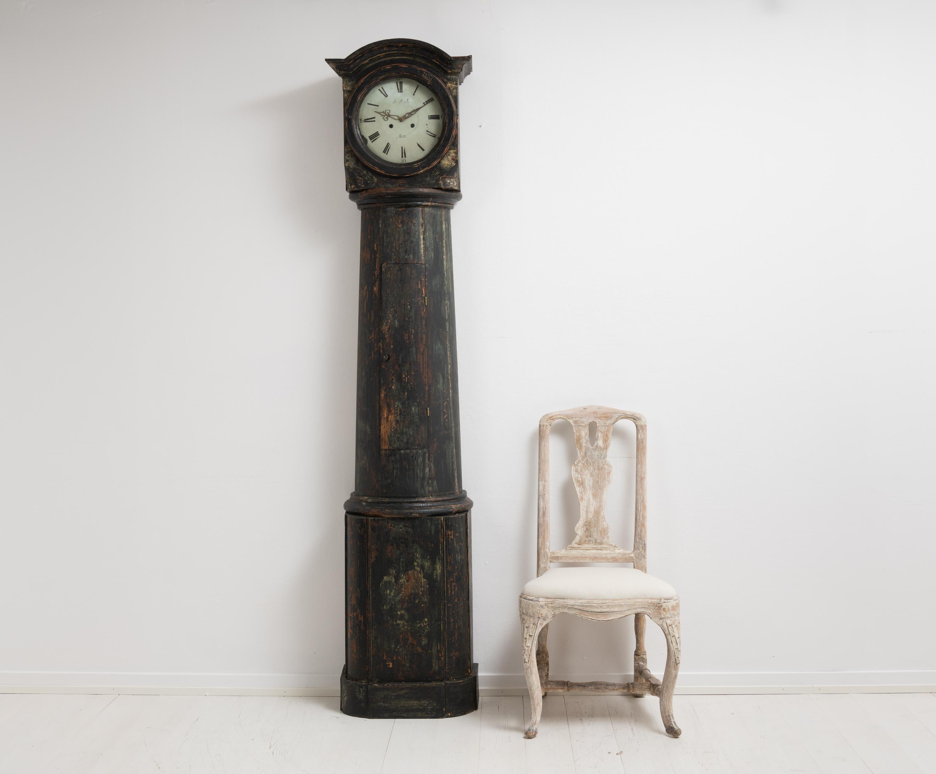 Swedish long case column clock in black made around 1820 to 1840. The clock is in the shape of a column with a square head and the original clock work. Made in painted pine with old black paint from the late 1800s. The old paint is distressed with a