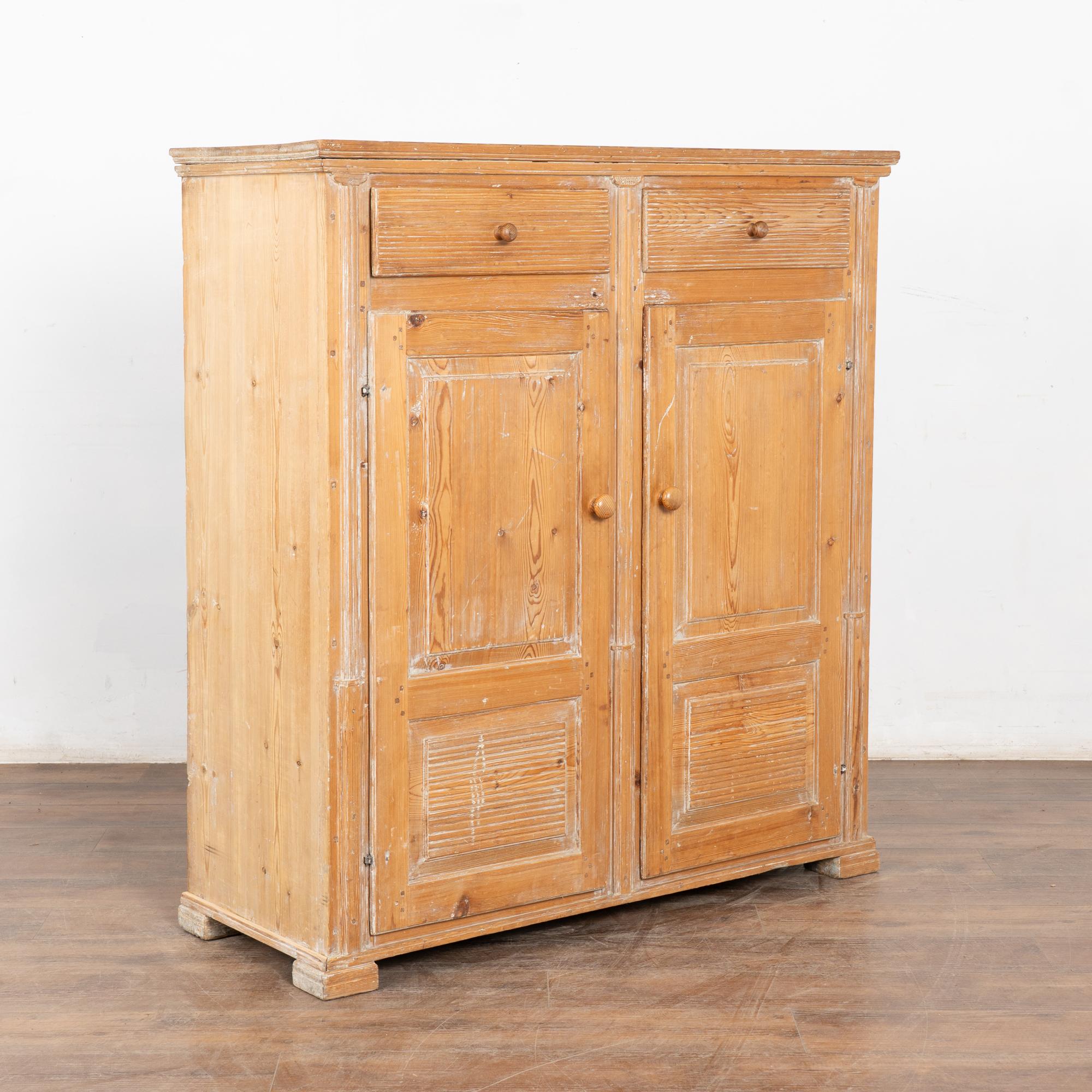 Questa credenza country svedese mantiene il suo fascino semplice con una finitura scrostata che completa il pino naturale.
L'interno rivela tre ripiani dietro due ante dell'armadio. 
Restaurato, stabile e pronto all'uso. Le porte si aprono con un