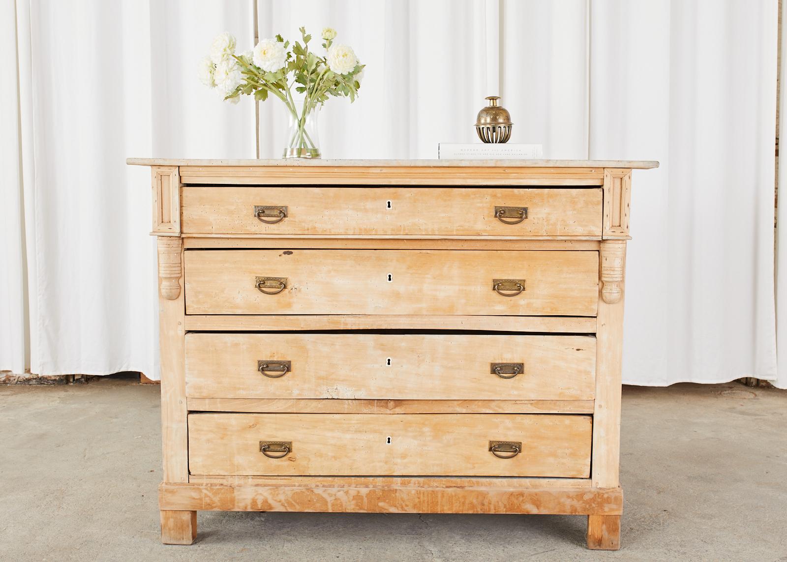 Rustic 19th century Swedish pine commode or chest of drawers featuring a bleached finish. The large chest has four generous wide storage drawers with brass pulls. The case has a beautifully aged patina on the washed pine. Solid and stable