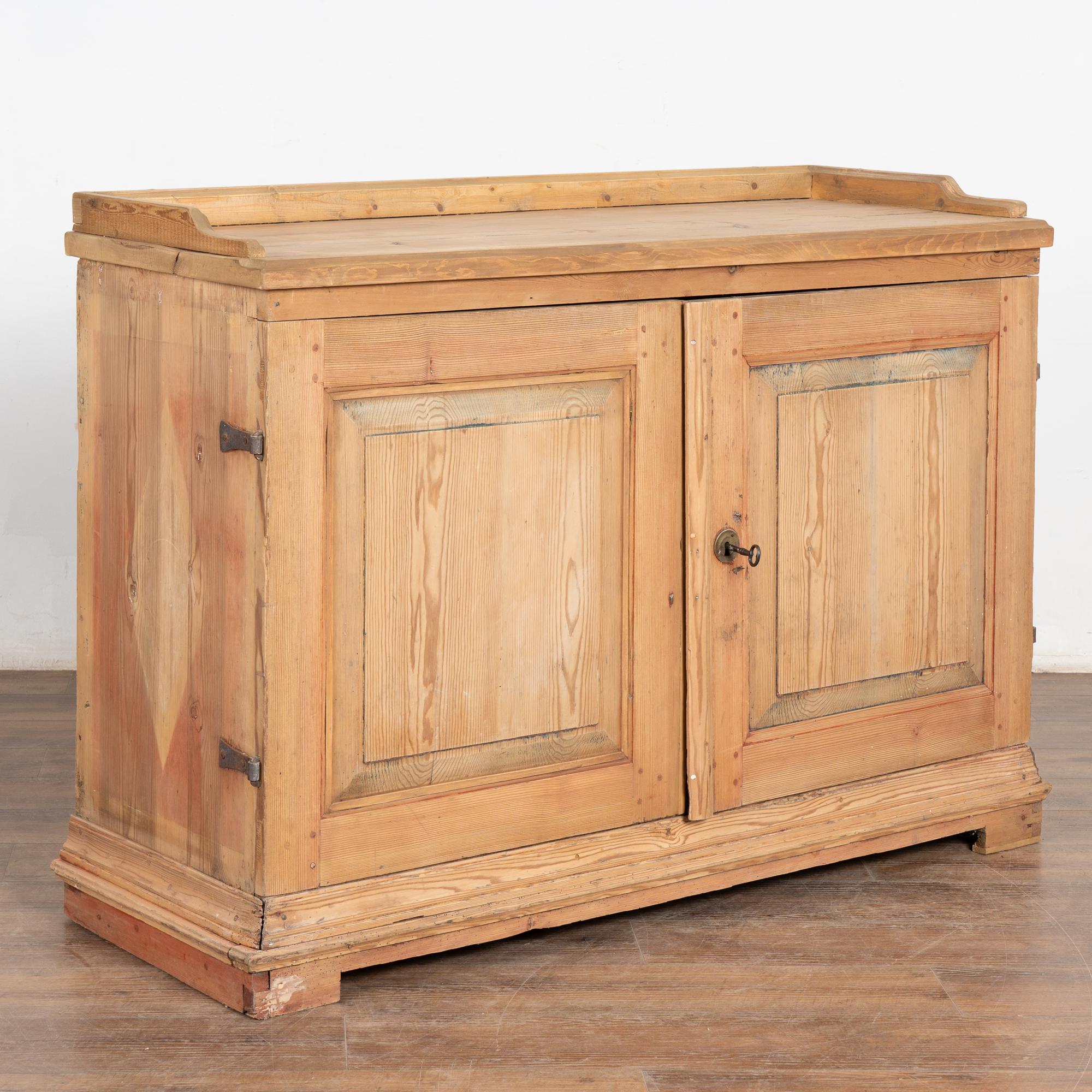 Questa credenza country svedese mantiene il suo fascino semplice con una finitura cerata sul pino naturale.
Si noti il contorno morbido di un diamante sui lati, con un debole residuo di rosso lungo i lati e i piedi e un debole blu lungo le porte del