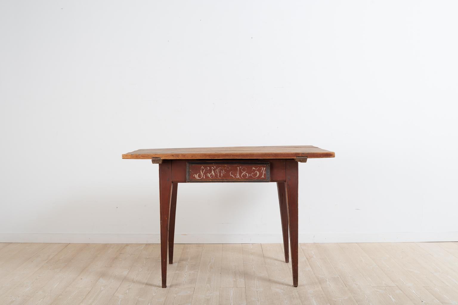 19th century provincial Gustavian table from northern Sweden. The table has straight tapered legs decorated with cannelures. It is in untouched original condition with original untouched paint. The monogram and dating 1834 on the drawer are also