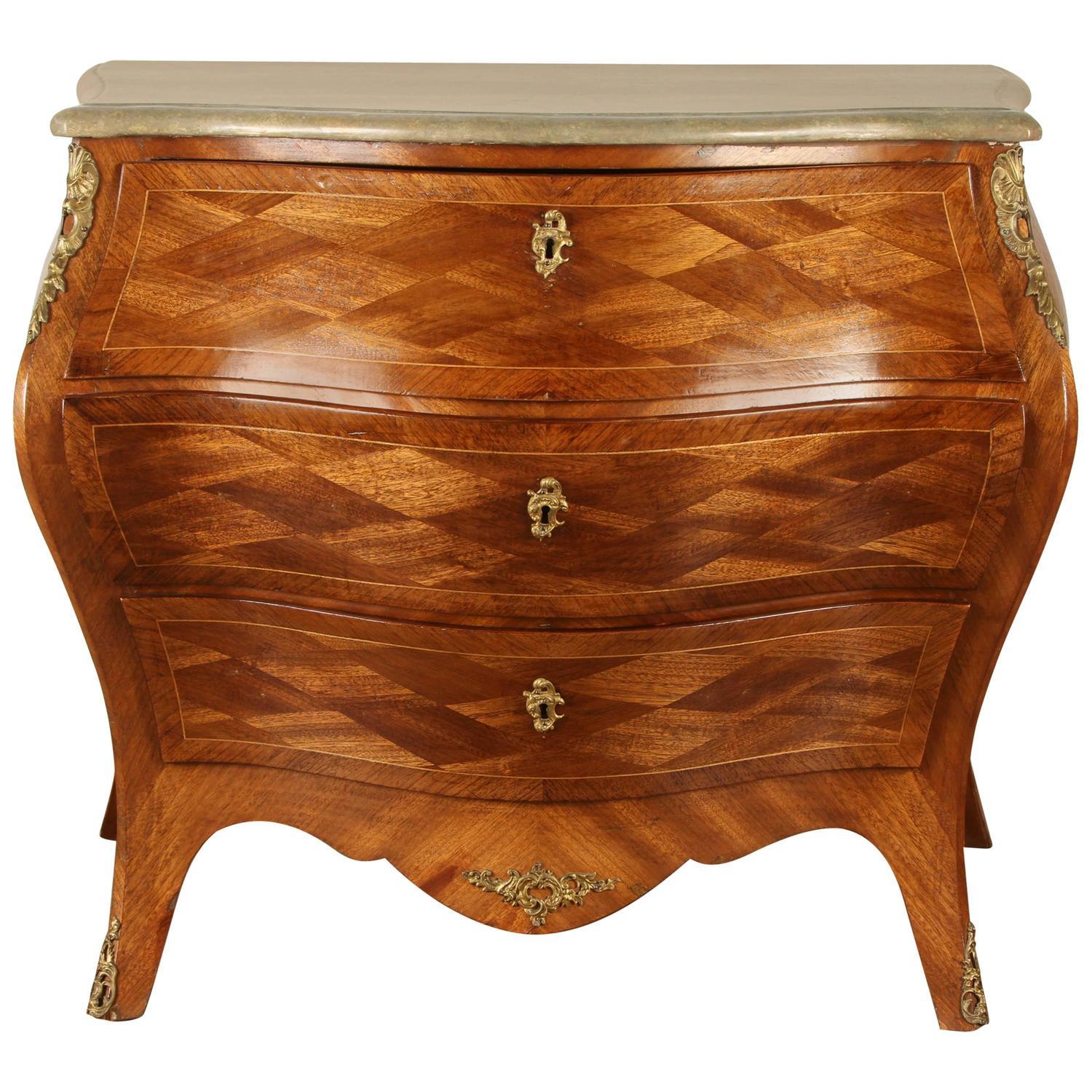 A Swedish Rococo Revival Bombay chest. This Rococo Revival chest is covered overall in parquetry, with gilt ormolu. It has three drawers. The top of the chest is in faux painted marble.