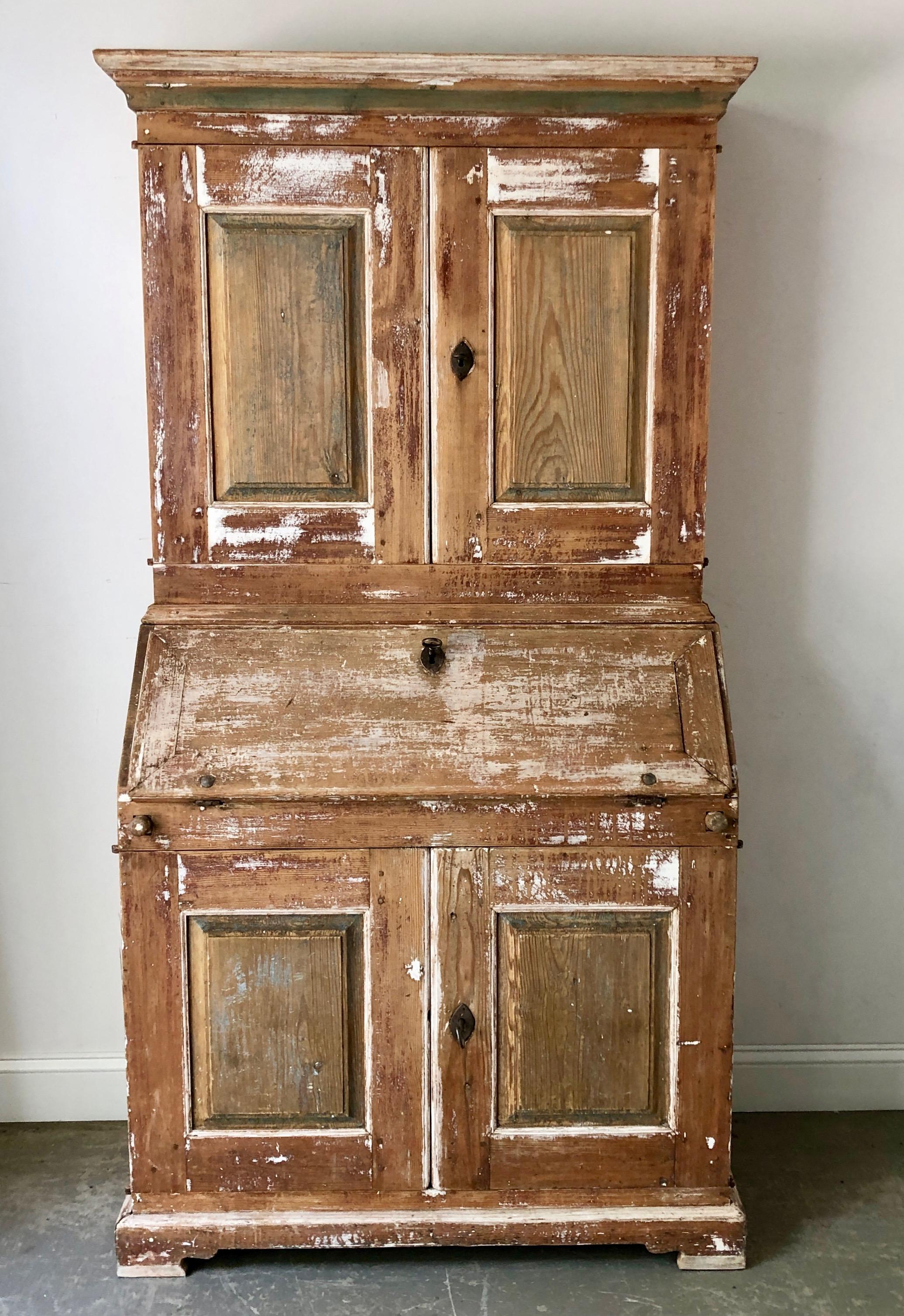 Charming 19th century Swedish country secretary with library cabinet in two parts with molded cornice and three fixed shelves behind the raised panel doors. The lower section has a slant front desk with a fitted interior over the two raised panel