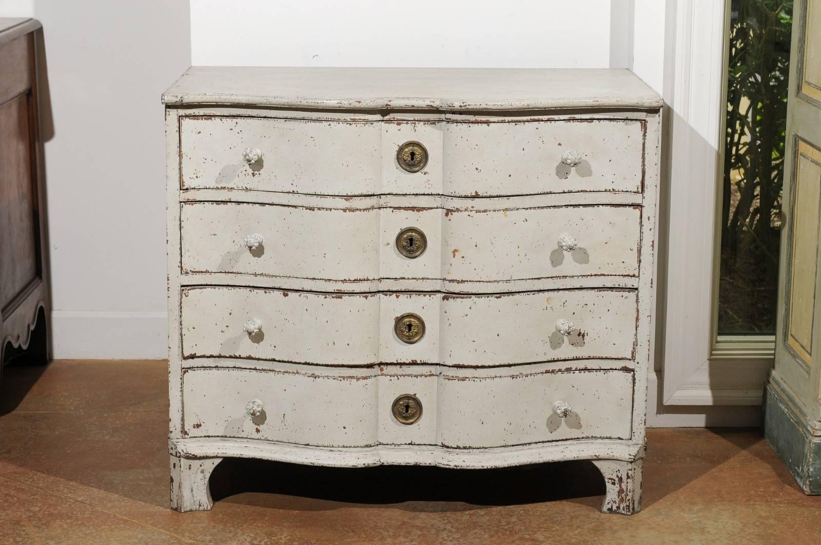 A Swedish painted wood serpentine four-drawer commode from the 19th century with bracket feet. This Swedish 19th century chest-of-drawers features a beautifully weathered finish, perfectly complimenting the crossbow shape of the piece. The façade