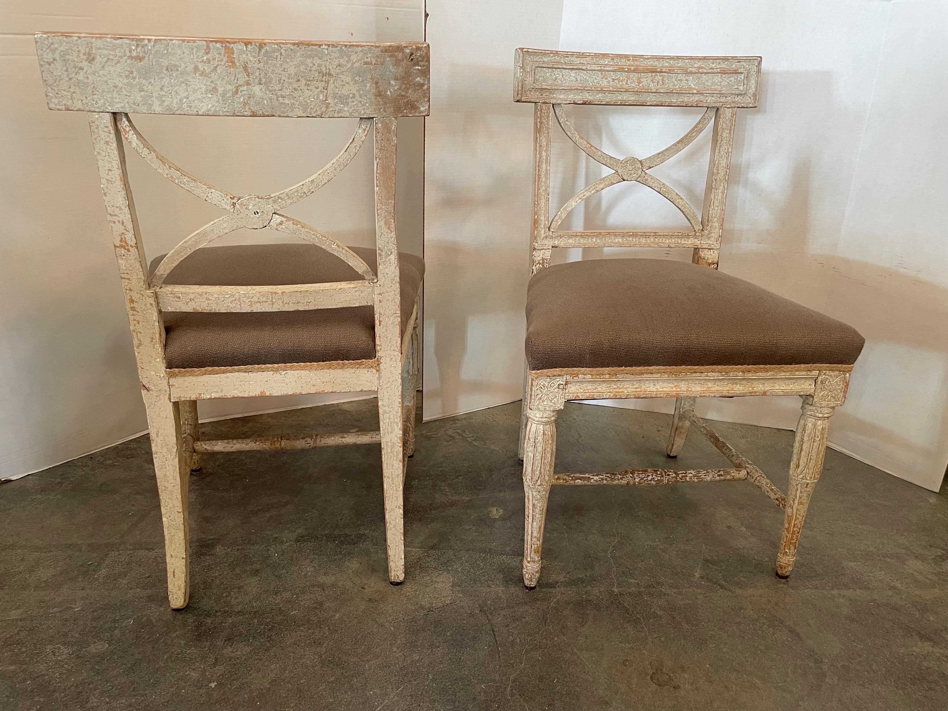 This Gustavian style scraped back painted chairs have a really handsome look with great patina and hints of pale blue plaster paint on creamy white.
They make a beautiful set around a casual table. They’re very solid and sturdy with subtle carvings