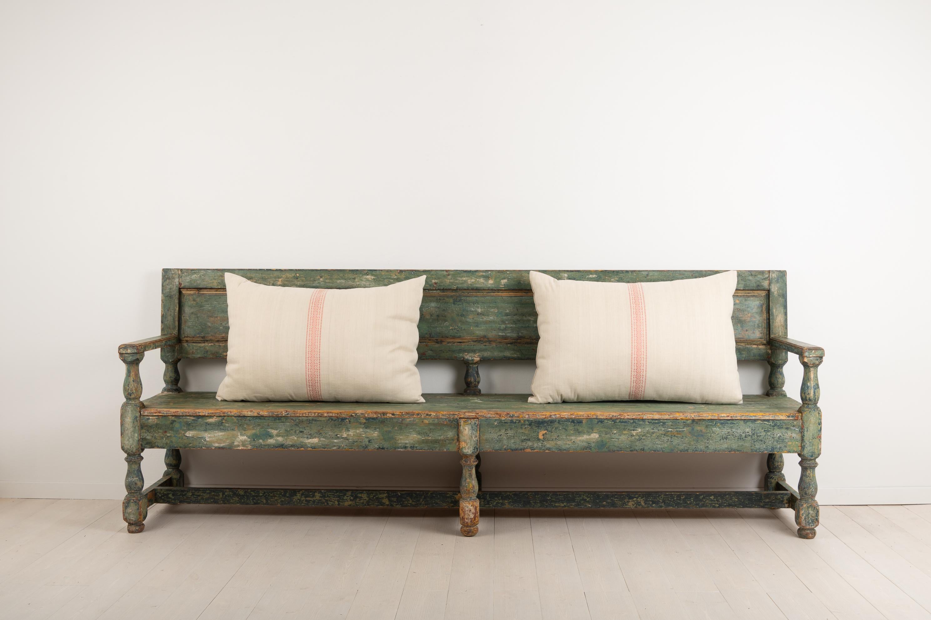 Swedish sofa bench in painted pine. The bench is Folk Art and made in Baroque style. The green paint is original and naturally distressed due to age and use. Originally from northern Sweden and made circa 1830. The bench is quite wide at just over 2