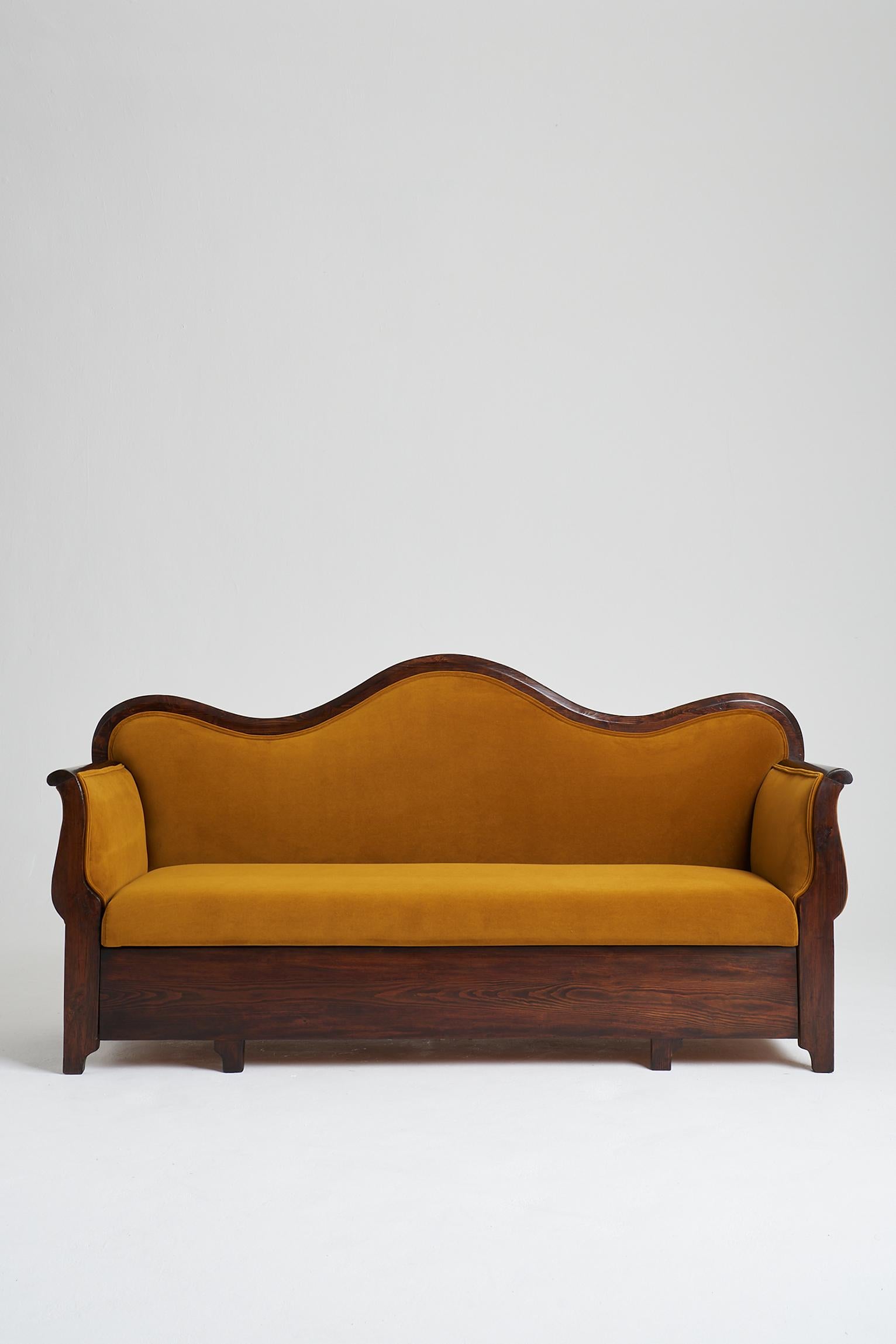 A 19th century stained pine sofa, the curved armrests flanking a bevelled and elegantly wavy back.
Newly upholstered in mustard velvet. 
Sweden, mid 19th century.