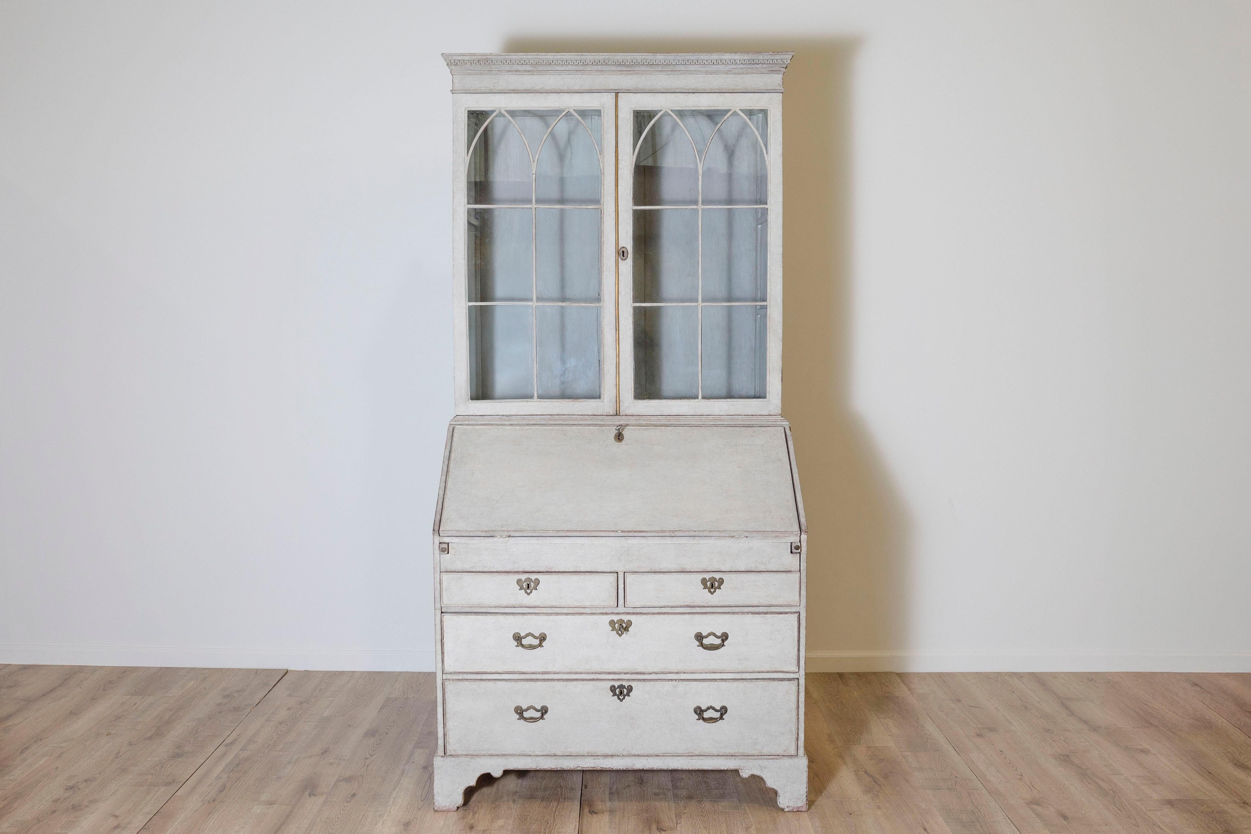 This beautiful 19th-century Swedish Gustavian secretary combines functionality with classic elegance. The top section features two lockable glass-paneled doors with original cast glass (one pane replaced over time) and two fixed-height shelves