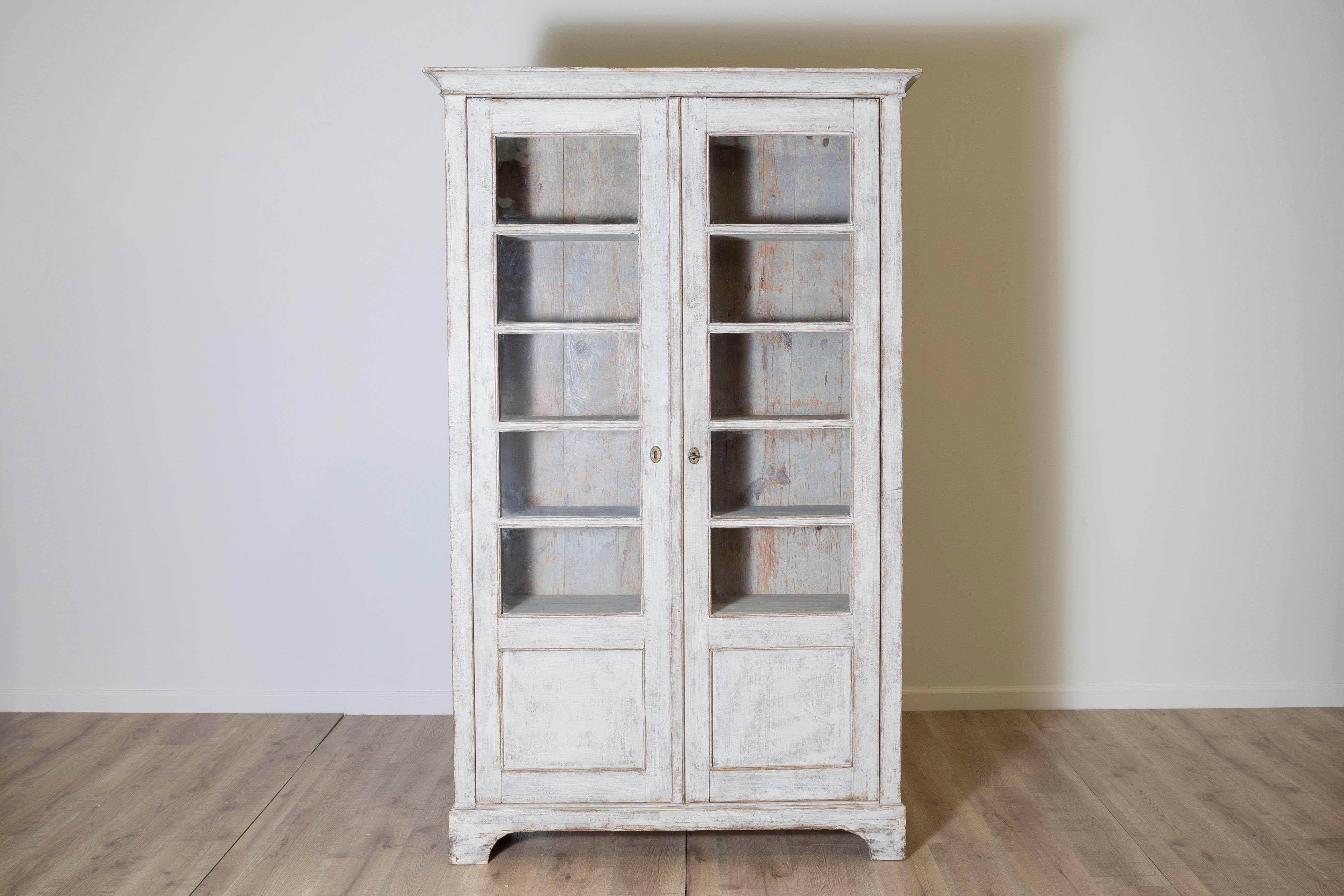Questa eccezionale credenza svedese, risalente al 1850 circa, è un notevole esempio di design classico scandinavo. Realizzato in pino massiccio, il pezzo conserva le porte in vetro originali, mostrando la sua autenticità e il suo charme. I pannelli