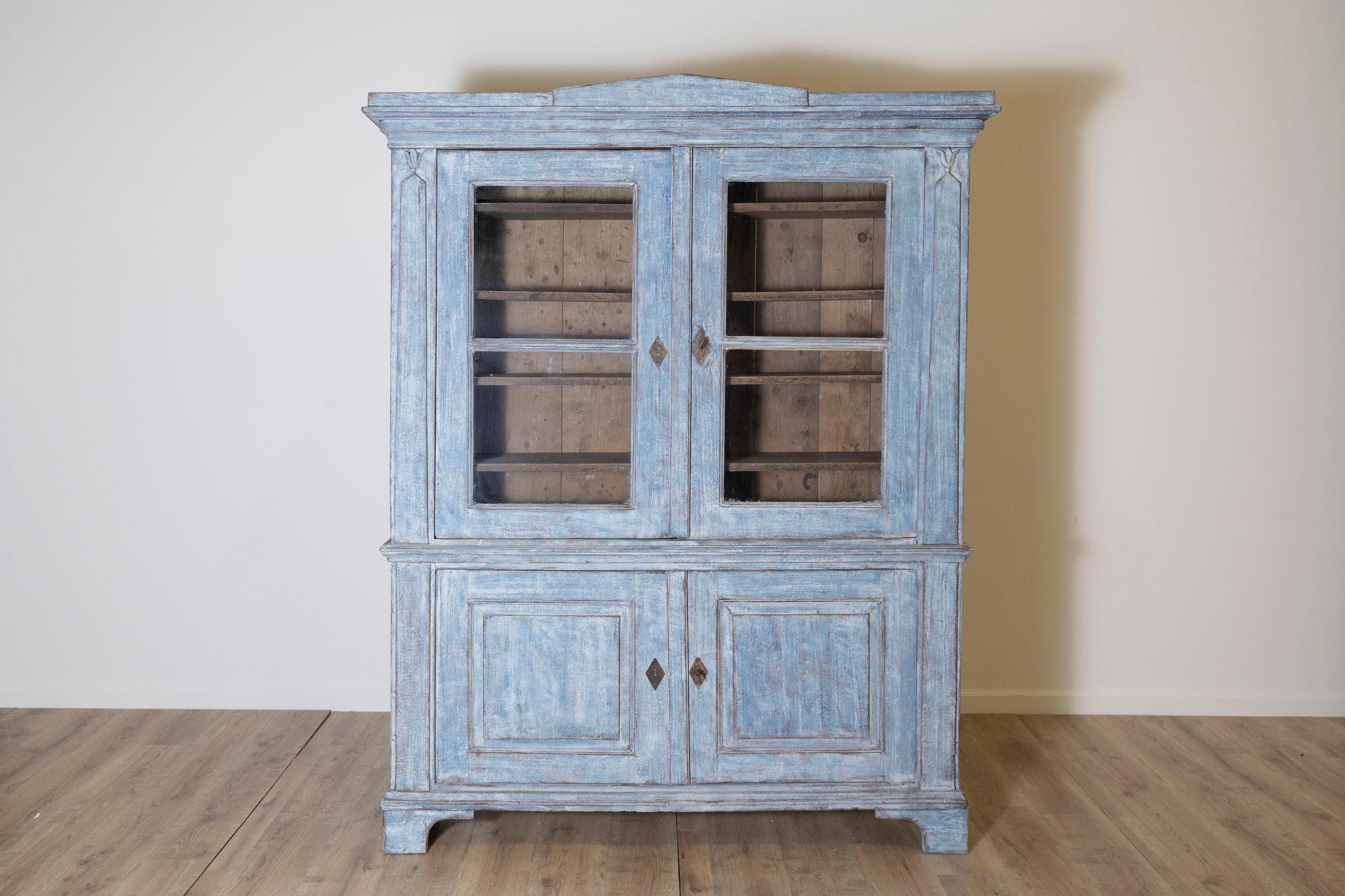 This stunning blue-painted Swedish vitrine cupboard, dating back to the early 1800s or earlier, is a magnificent example of classic Scandinavian craftsmanship. Its original distressed finish offers a charming patina, highlighting the piece’s rich