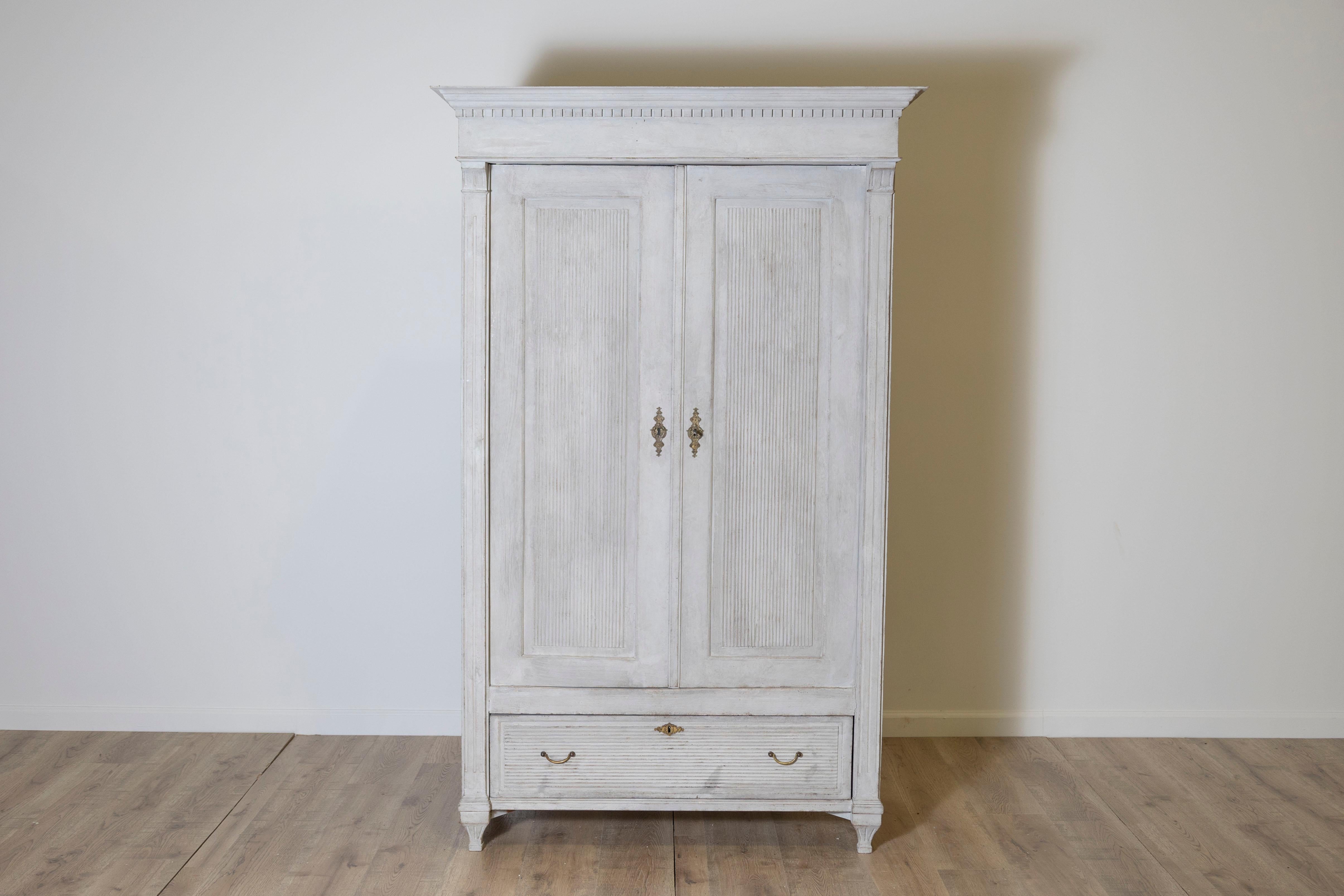This exquisite Gustavian wardrobe exudes timeless elegance and functionality. Featuring two paneled doors adorned with decorative vertical milling cutters, the design highlights the understated sophistication characteristic of Gustavian style. Below