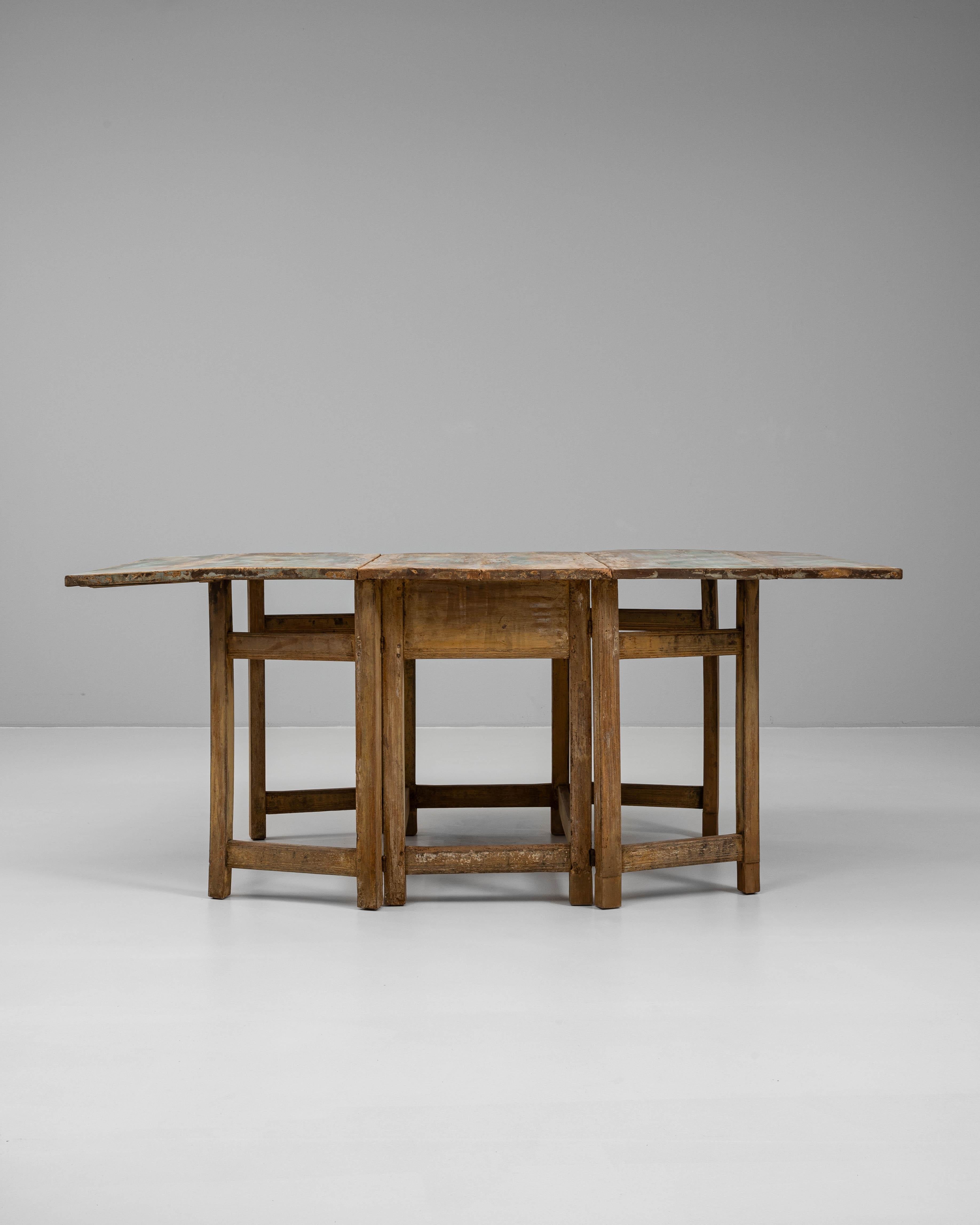 This 19th Century Swedish drop-leaf table is a charming example of functional rustic design with timeless appeal. Crafted from solid wood, the table features a beautifully worn patinated surface in soft, muted tones that speak to its age and
