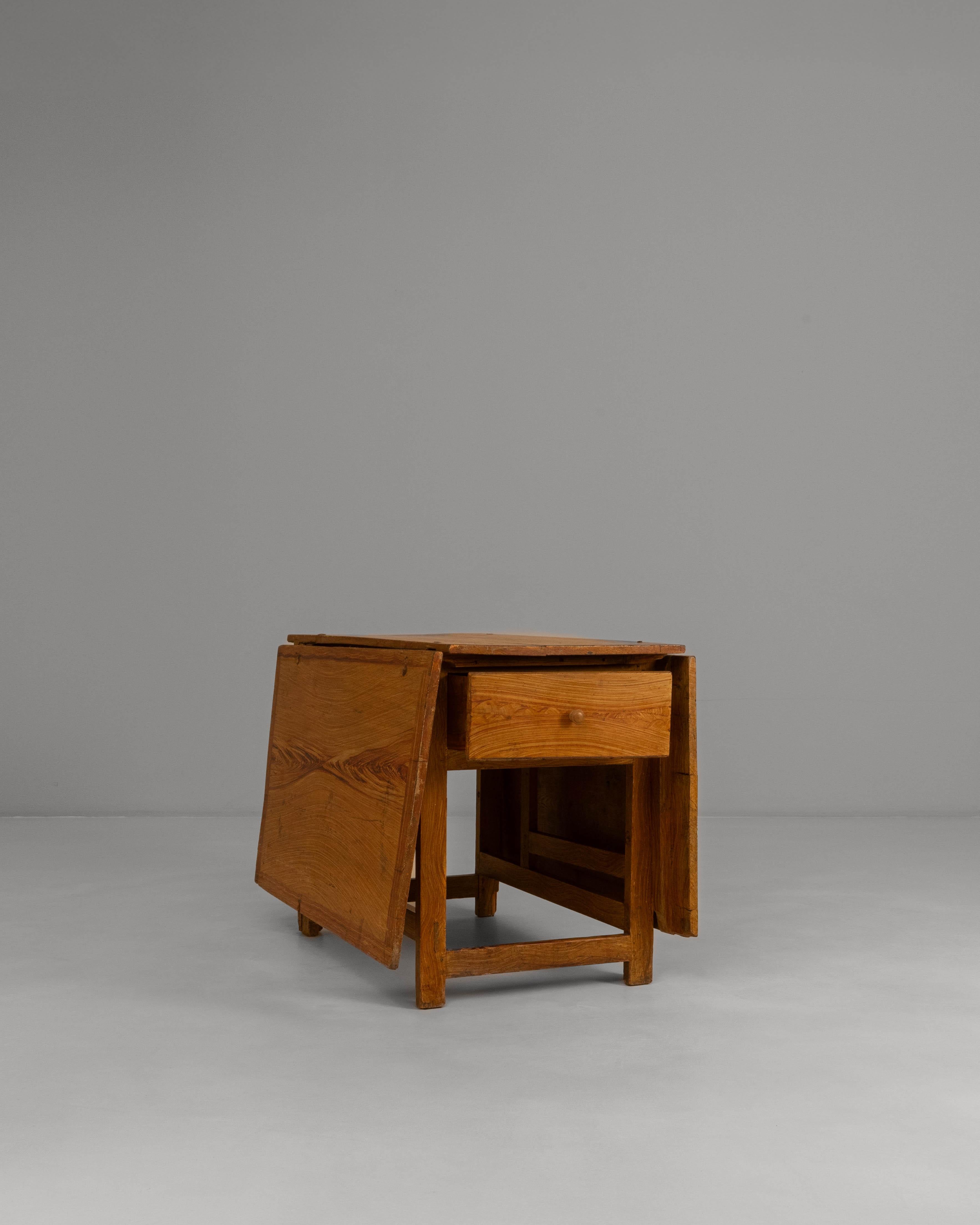 This 19th Century Swedish wooden drop-leaf table features a classic functional design enhanced by its beautifully preserved original patina. Crafted from solid wood, the table showcases a warm, timeworn surface that highlights the natural grain and