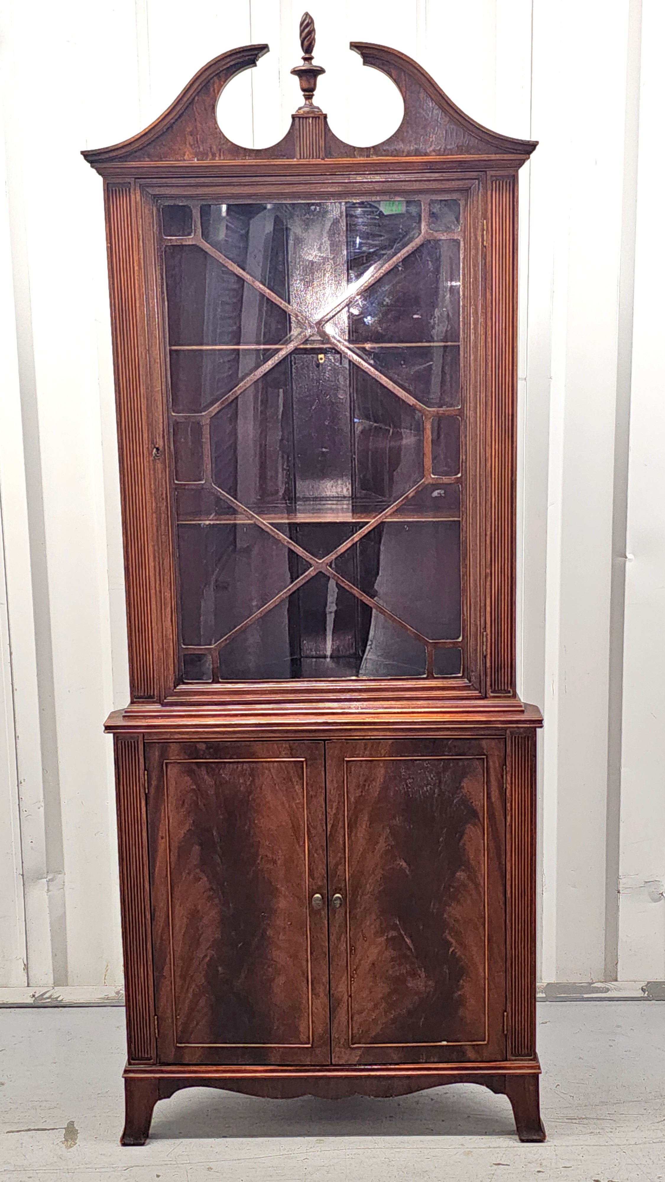 A 19th Century Swirl  Mahogany Georgian Style corner cabinet. Glass front with locking door with key. Removable wood shelves. Measures 29