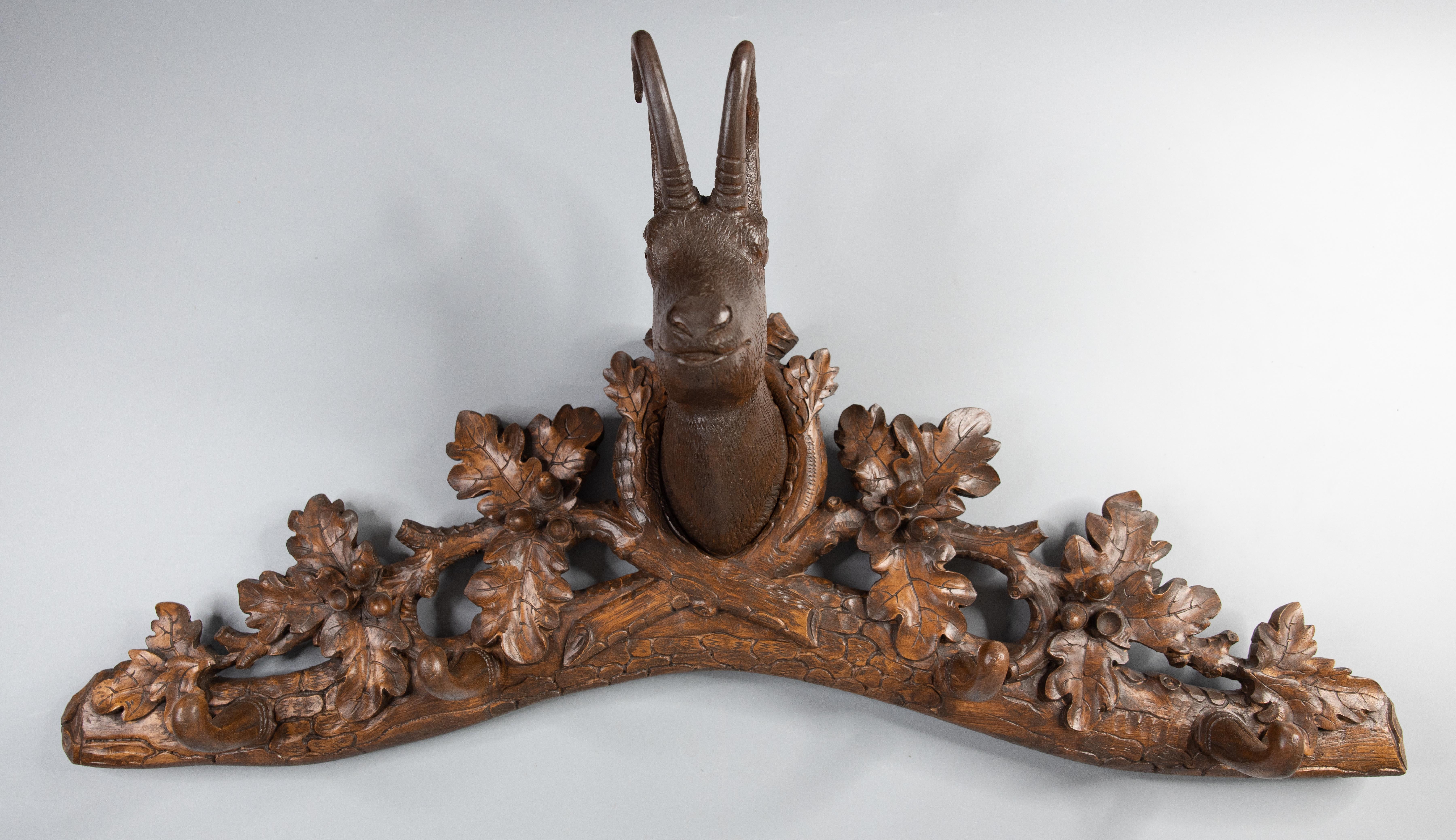 A superb antique Black Forest chamois coat and hat rack made in Switzerland, circa 1880. This fine rack features a hand carved handsome chamois surrounded by intricately carved leaves and four wooden hooks for hanging hats or coats. It's perfect for