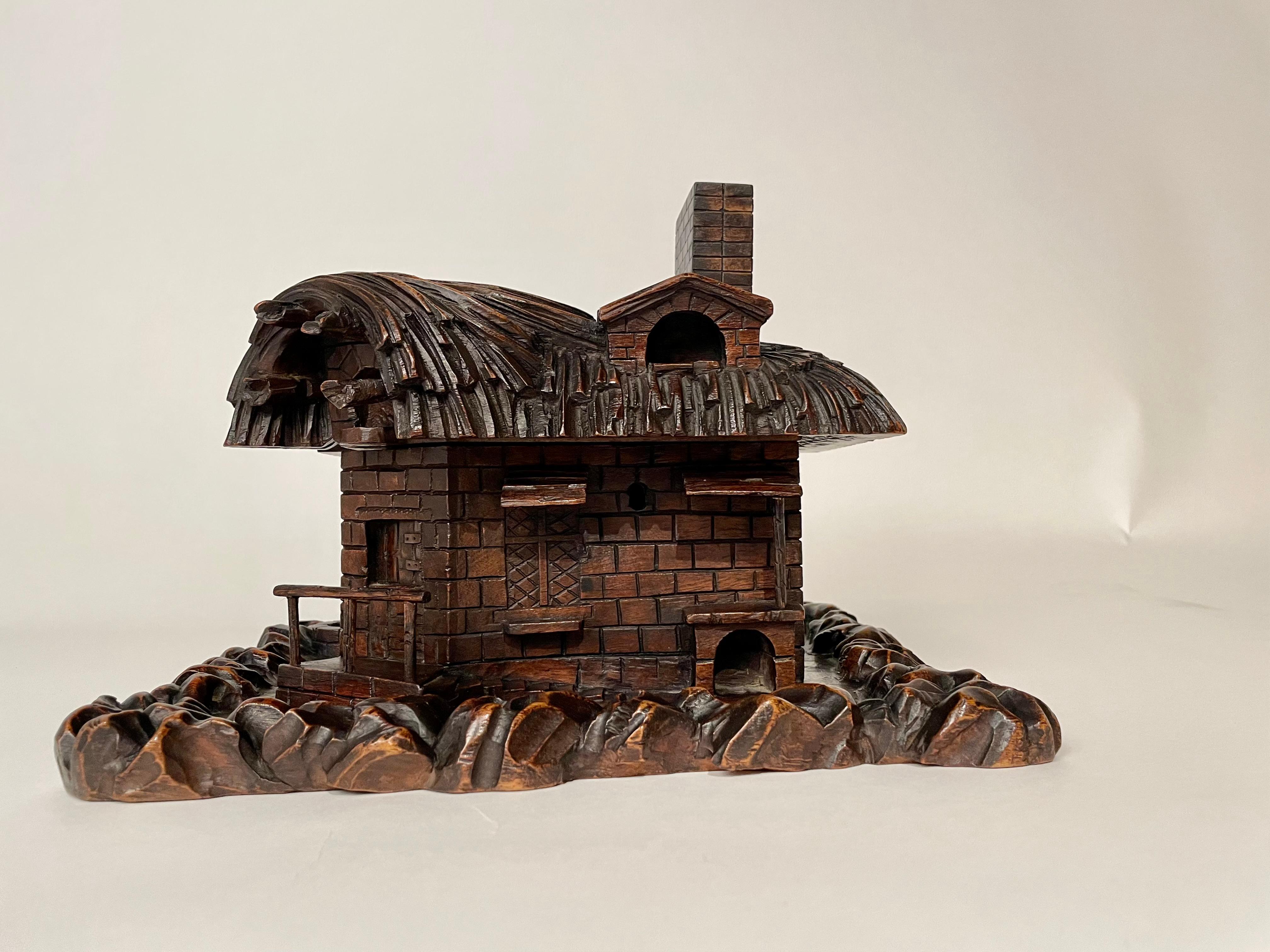 Fantastic and rare example of Black Forest folk art, a tour de force of carving by a master woodworker. This lift top box in the form of a thatched cottage has many wonderful details. The various surfaces of the walls, the amazing thatched roof, the