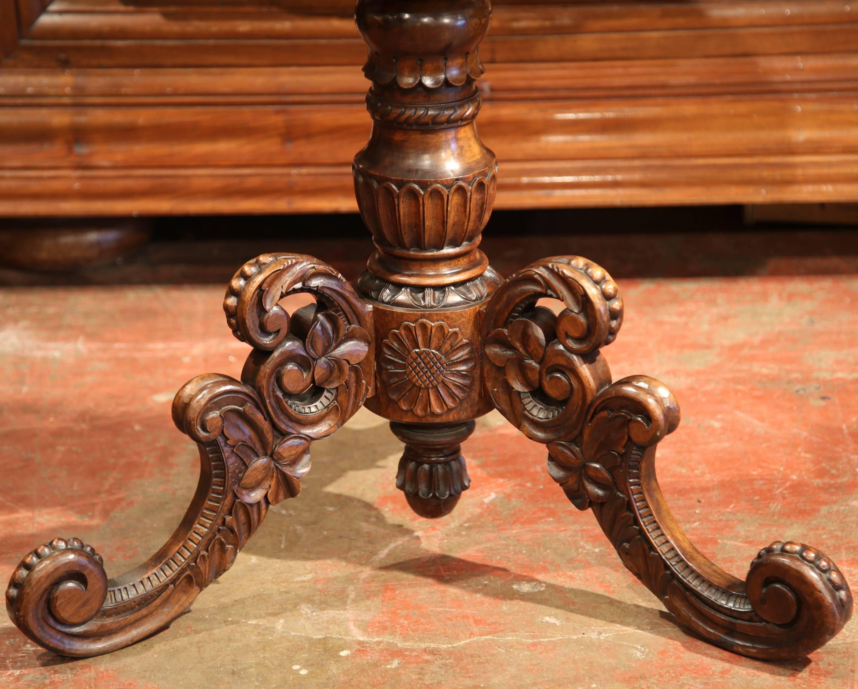 Crafted in Switzerland, circa 1870 and oval in shape, the antique occasional table features a tilt-top surface over a carved stem and an ornate pedestal base ending with three scrolled legs. The shaped and scalloped top has beautiful, illustrative