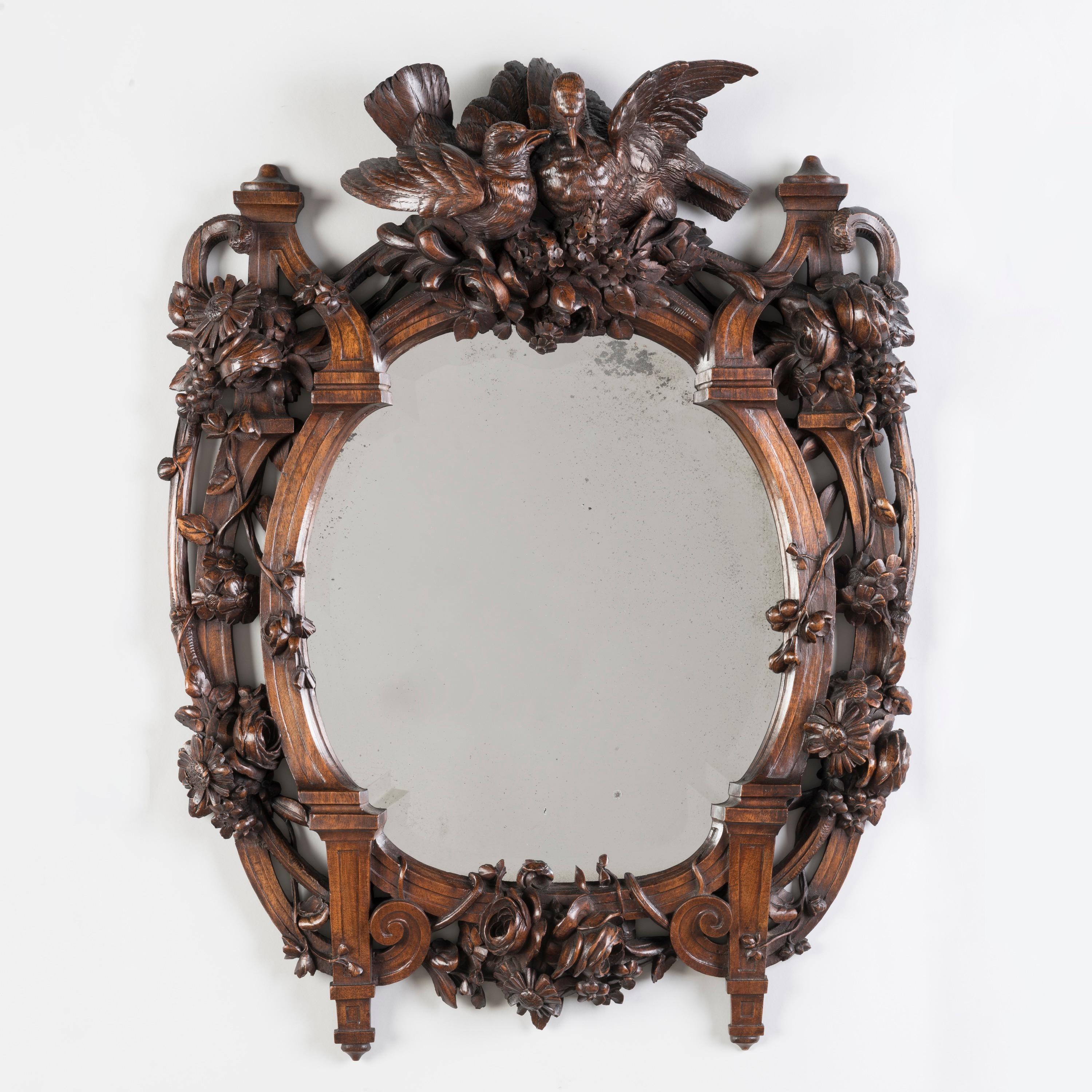 Miroir sculpté de la forêt noire

Sculptée dans du noyer, la plaque de miroir ovale biseautée s'inscrit dans un cadre architectural et flanque des branches rustiques typiques des sculptures de la Forêt-Noire,  entrelacés de branches fleuries de