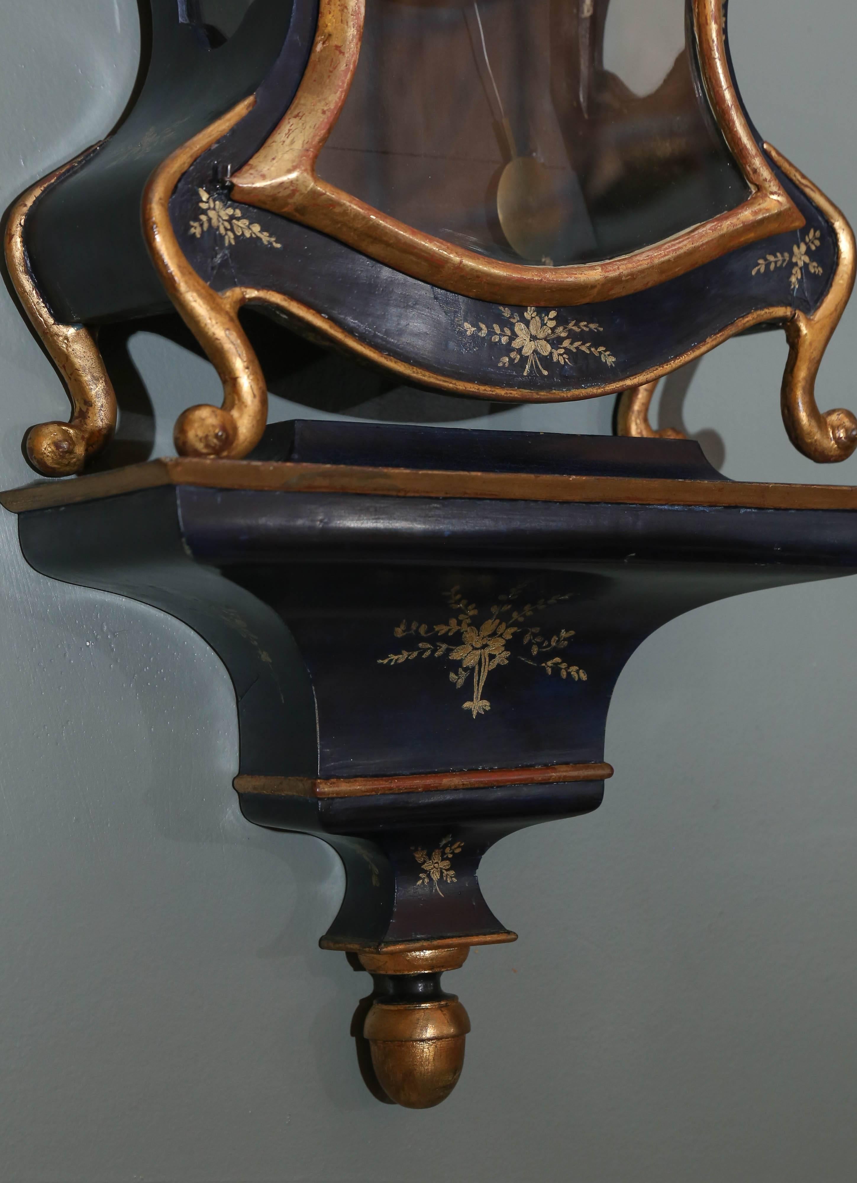 19th century Swiss lacquer cartel clock is simple in design with painted gold.
There is gilt banding and painted flower sprigs painted around front. On top is a gilt ball finial.
Pedestal features same gilt banding and painted flowers. At the