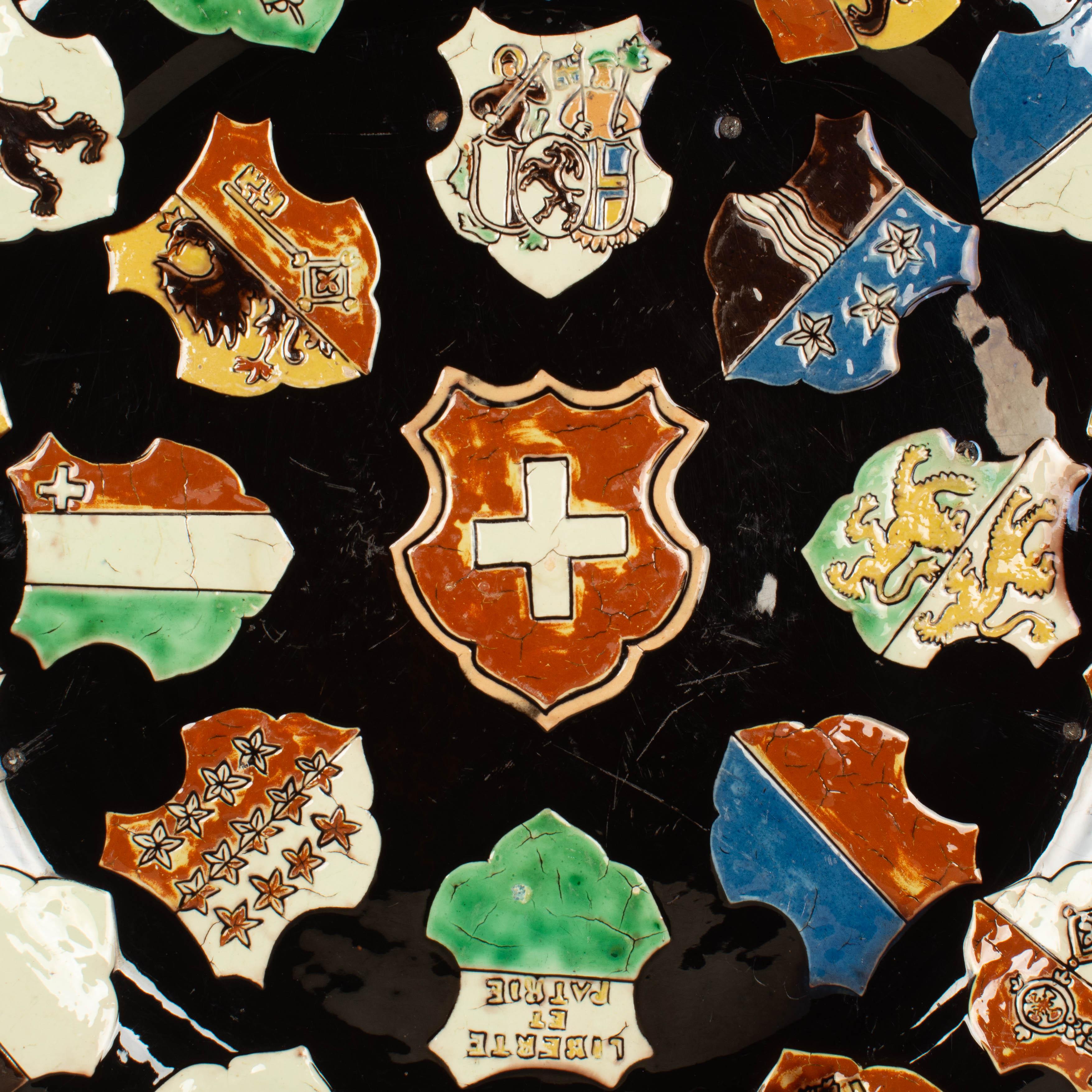 A 19th century Swiss glazed ceramic decorative platter or charger, hand-painted with images of coat of arms or crests of the Swiss provinces. Holes pierced on the back with wire for hanging on the wall. Small chip on back and minor losses to glaze.