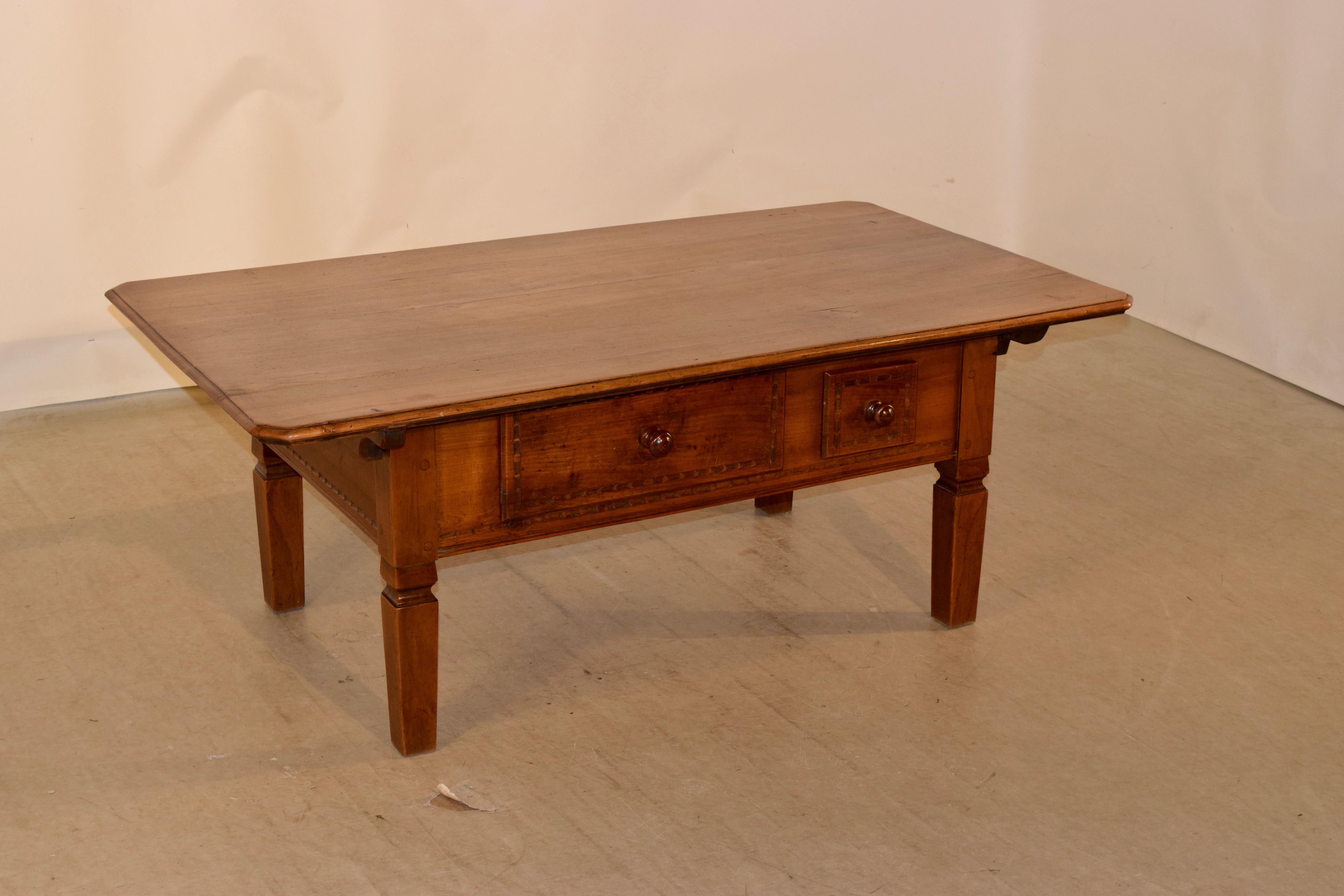 19th century Swiss coffee table made from fruitwood. The top is made from gorgeous planks with wonderful graining and a beveled edge with chamfered corners. The apron is simple and has two drawers in the front with carved decorated drawer fronts.